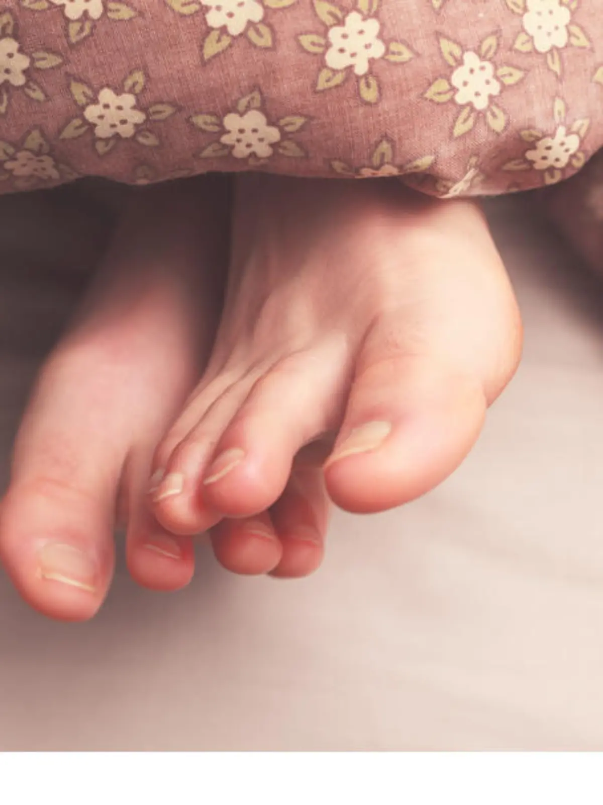 Young woman's feet in bed under the covers