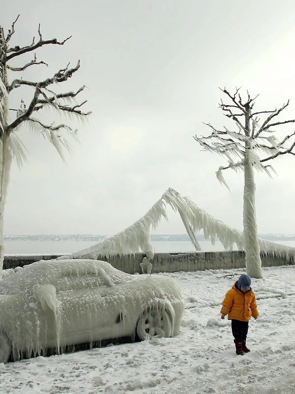 People admire ice-covered cars, light garlands and trees at the shores of lake Geneva near Versoix, Switzerland, Friday 28 January 2005. Strong winds forced lake water to crash over the shoreline, creating bizarre ice-sculptures. EPA/MARTIAL TREZZINI +++(c) dpa - Report+++