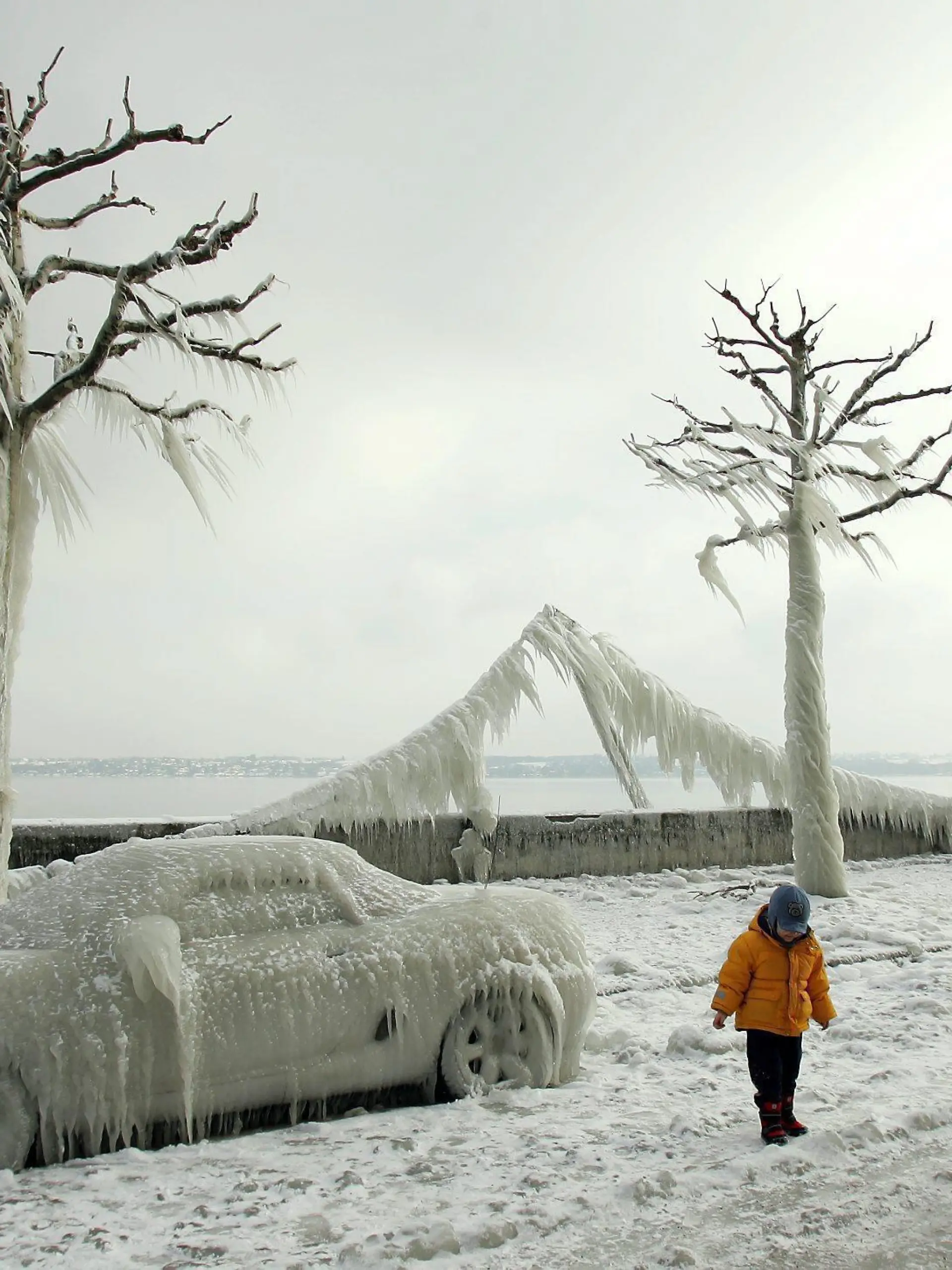 People admire ice-covered cars, light garlands and trees at the shores of lake Geneva near Versoix, Switzerland, Friday 28 January 2005. Strong winds forced lake water to crash over the shoreline, creating bizarre ice-sculptures. EPA/MARTIAL TREZZINI +++(c) dpa - Report+++
