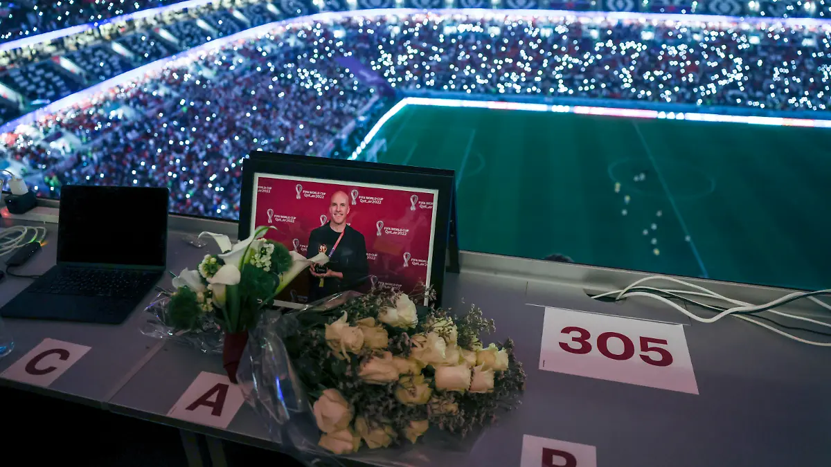(221210) -- AL KHOR, Dec. 10, 2022 (action press/Xinhua) -- Flowers and a picture of the journalist Grant Wahl of the United States who collapsed and died in the stadium's press area while covering the match between Argentina and Netherlands are seen in the media tribune during the Quarterfinal between England and France at the 2022 FIFA World Cup at Al Bayt Stadium in Al Khor, Qatar, Dec. 10, 2022. (action press/Xinhua/Xu Zijian) / action press