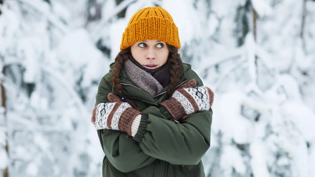 Waist up portrait of pretty young woman freezing in cold winter forest, copy space