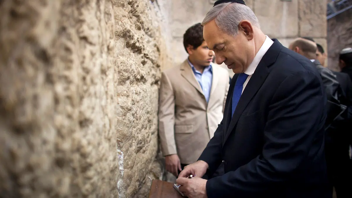 Israel's Prime Minister Benjamin Netanyahu (R) writes a note to place in the Western Wall in Jerusalem's Old City after casting his ballot for the parliamentary election January 22, 2013. Israelis look set to elect Prime Minister Benjamin Netanyahu to a third term with a smaller majority on Tuesday, pushing the Jewish State even further to the right, away from peace with Palestinians and towards a showdown with Iran. REUTERS/Uriel Sinai/Pool (JERUSALEM - Tags: POLITICS ELECTIONS RELIGION)