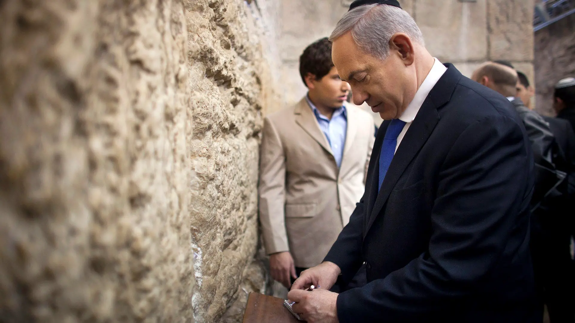 Israel's Prime Minister Benjamin Netanyahu (R) writes a note to place in the Western Wall in Jerusalem's Old City after casting his ballot for the parliamentary election January 22, 2013. Israelis look set to elect Prime Minister Benjamin Netanyahu to a third term with a smaller majority on Tuesday, pushing the Jewish State even further to the right, away from peace with Palestinians and towards a showdown with Iran. REUTERS/Uriel Sinai/Pool (JERUSALEM - Tags: POLITICS ELECTIONS RELIGION)