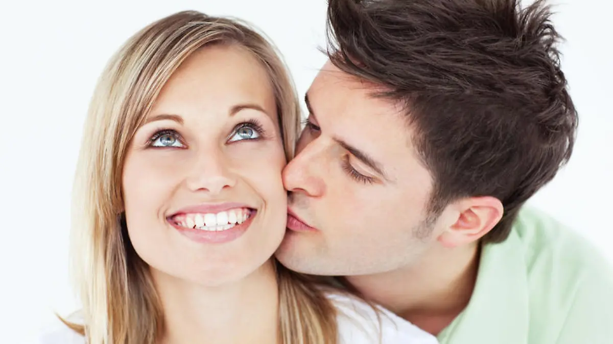 careful man kissing his smiling girlfriend against a white background