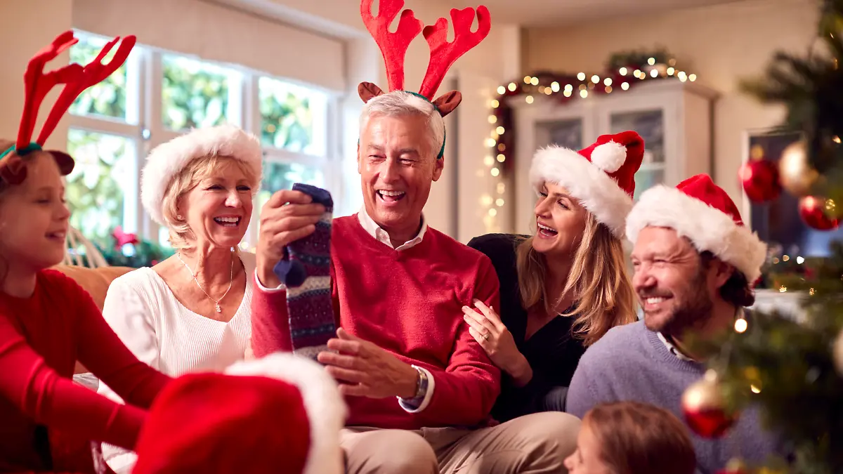 Multi-Generation Family Exchanging And Opening Gifts Around Christmas Tree At Home