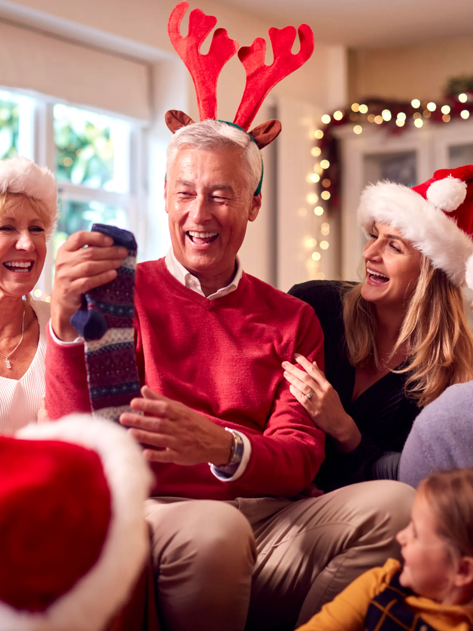 Multi-Generation Family Exchanging And Opening Gifts Around Christmas Tree At Home