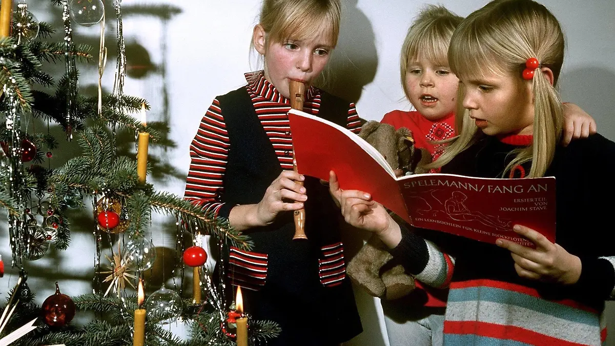 Zwei Mädchen singen am Heiligen Abend neben dem Christbaum stehend Weihnachtslieder und werden von ihrer Schwester auf der Blockflöte begleitet (undatiertes Archivfoto). Musikwissenschaftler, Politiker und Prominente schlagen Alarm: Es wird kaum noch gesungen unter Deutschlands Christbäumen. Statt aus geübten Kehlen von Mutter, Vater und Kind ertönen die Weihnachtslieder am Heiligen Abend auf Knopfdruck aus dem CD-Player. Die Familie lauscht, genießt - und schweigt. "Es ist ein Verfall der Singkultur zu beobachten", sagt der Musikpsychologe Karl Adamek. Foto: Jürgen Sasse dpa (zu dpa-Korr.: "'Stille Nacht' wird immer stiller: kaum noch Gesang unterm Christbaum" vom 21.12.2003)