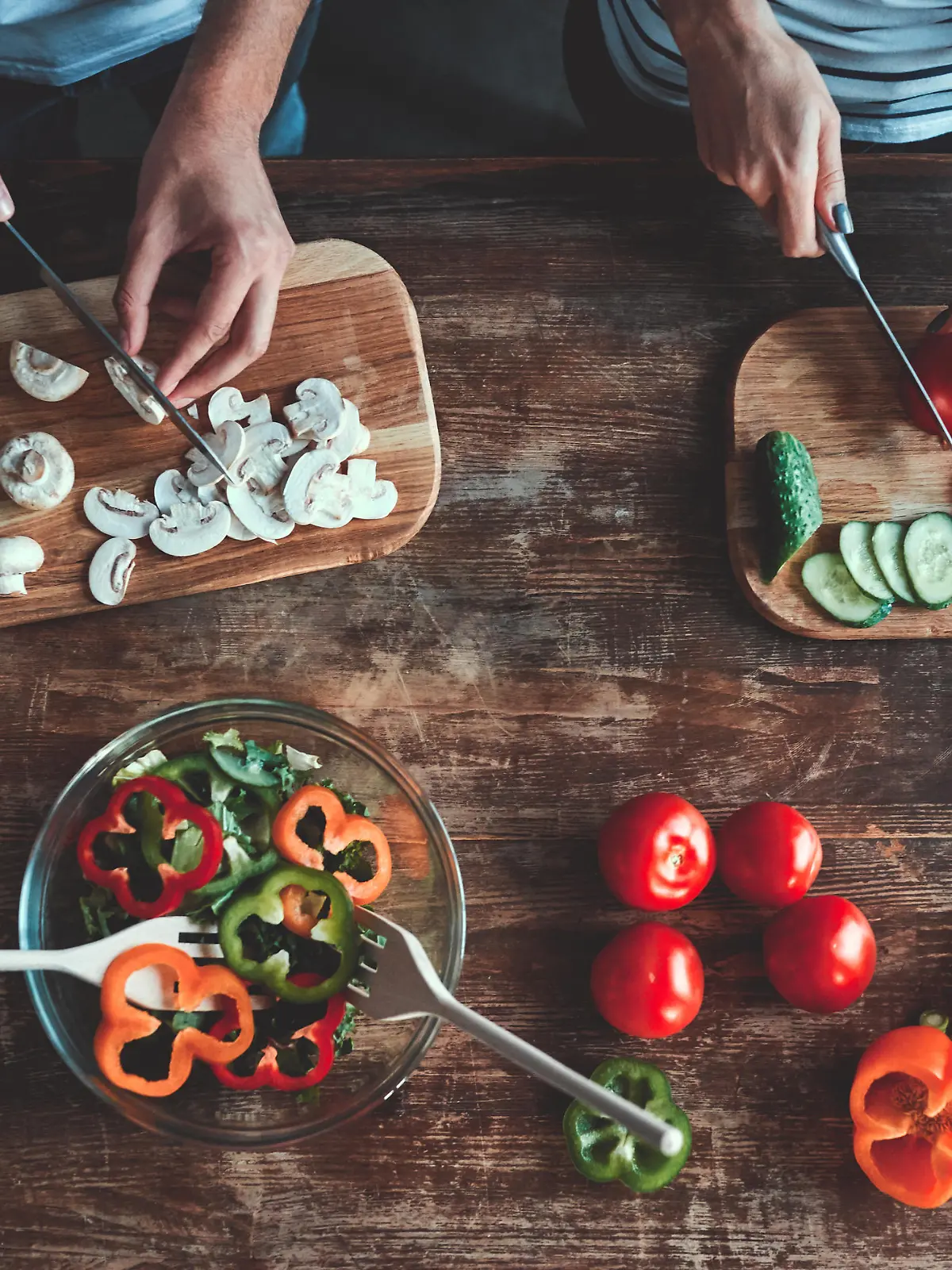 Cropped image of romantic couple is cooking on kitchen. Handsome man and attractive young woman are having fun together while making salad. Healthy lifestyle concept.