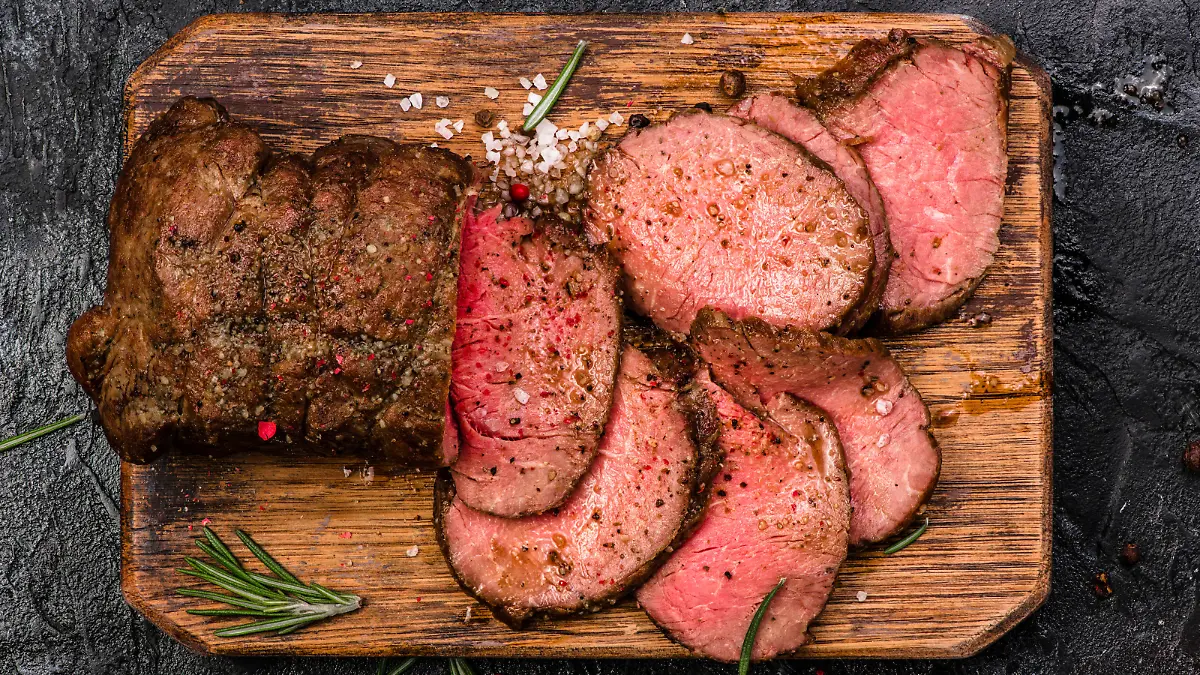 Roast beef on cutting board with salt and pepper. Top view.