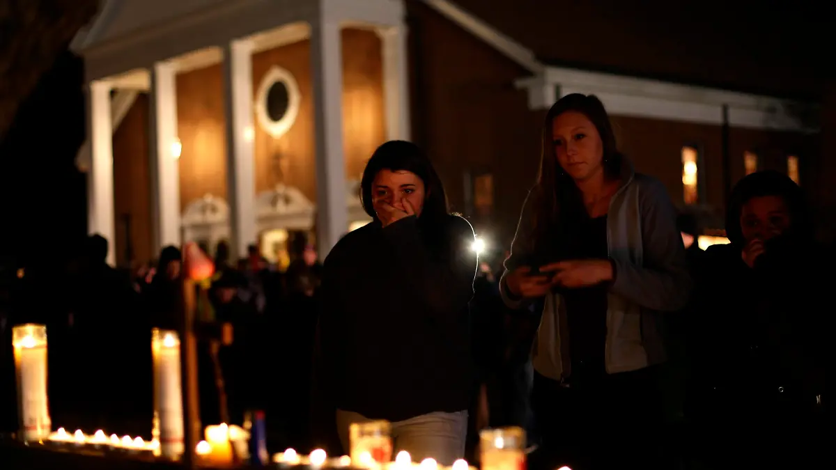 A woman covers her mouth as others look on stand near candles outside Saint Rose of Lima Roman Catholic Church near Sandy Hook Elementary School, where a gunman opened fire on school children and staff in Newtown, Connecticut December 14, 2012. A heavily armed gunman opened fire on school children and staff at a Connecticut elementary school on Friday, killing at least 28 people, including 20 children, in the latest in a series of shooting rampages that have tormented the United States this year. REUTERS/Joshua Lott (UNITED STATES - Tags: CRIME LAW EDUCATION)