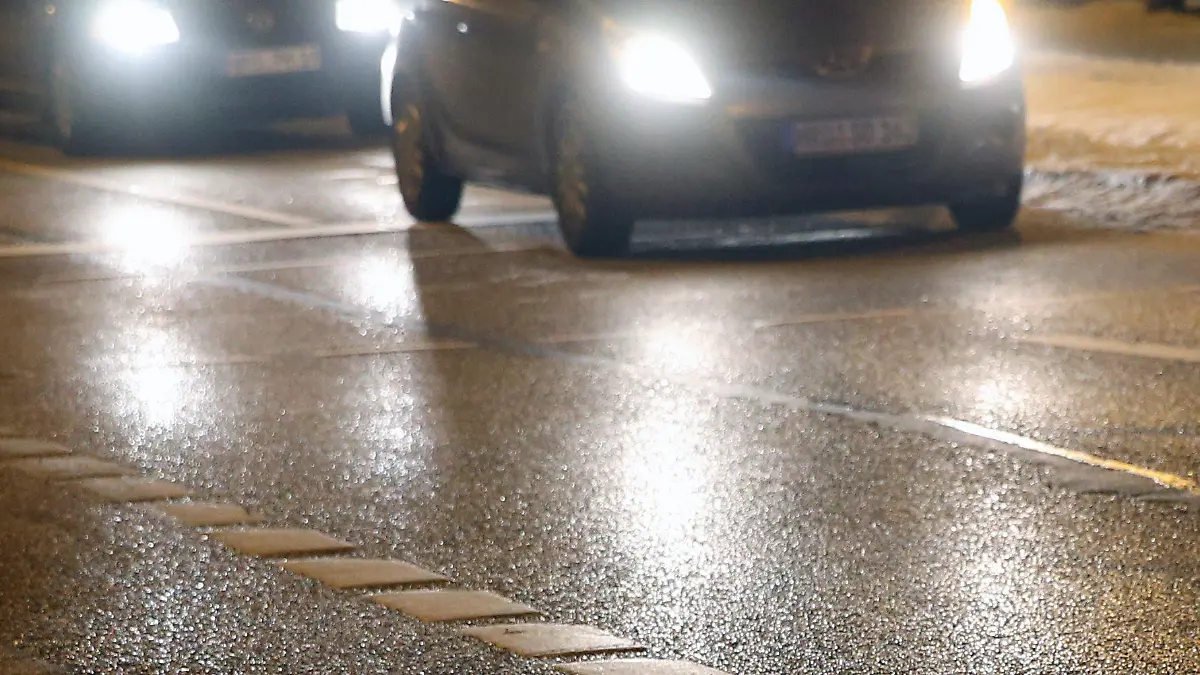 Das Licht von Autoscheinwerfern spiegelt sich am Abend des 14.12.2012 auf einer Straße in Rostock (Mecklenburg-Vorpommern). Mit dem Durchzug einer Regenfront vom 14.-15.12.2012 muss auch im Norden Deutschlands mit Blitzeis gerechnet werden. Foto: Bernd Wüstneck/dpa  +++(c) dpa - Bildfunk+++