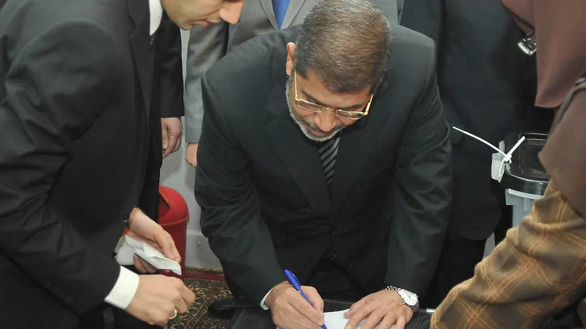 Egypt's President Mohamed Mursi signs his registration form at a polling station before casting his vote during a referendum on the new Egyptian constitution in Cairo December 15, 2012. Egyptians voted on Saturday on a constitution promoted by its Islamist backers as the way out of a prolonged political crisis and rejected by opponents as a recipe for further divisions in the Arab world's biggest nation. REUTERS/Egyptian Presidency/Handout (EGYPT - Tags: POLITICS ELECTIONS) FOR EDITORIAL USE ONLY. NOT FOR SALE FOR MARKETING OR ADVERTISING CAMPAIGNS. THIS IMAGE HAS BEEN SUPPLIED BY A THIRD PARTY. IT IS DISTRIBUTED, EXACTLY AS RECEIVED BY REUTERS, AS A SERVICE TO CLIENTS
