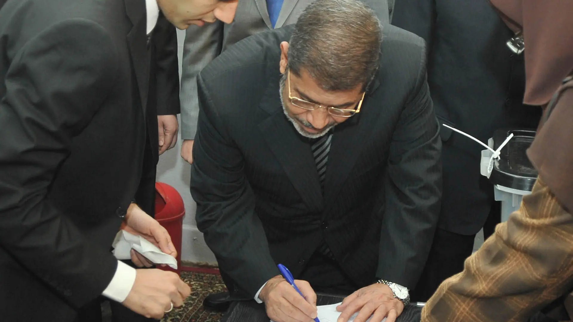 Egypt's President Mohamed Mursi signs his registration form at a polling station before casting his vote during a referendum on the new Egyptian constitution in Cairo December 15, 2012. Egyptians voted on Saturday on a constitution promoted by its Islamist backers as the way out of a prolonged political crisis and rejected by opponents as a recipe for further divisions in the Arab world's biggest nation. REUTERS/Egyptian Presidency/Handout (EGYPT - Tags: POLITICS ELECTIONS) FOR EDITORIAL USE ONLY. NOT FOR SALE FOR MARKETING OR ADVERTISING CAMPAIGNS. THIS IMAGE HAS BEEN SUPPLIED BY A THIRD PARTY. IT IS DISTRIBUTED, EXACTLY AS RECEIVED BY REUTERS, AS A SERVICE TO CLIENTS