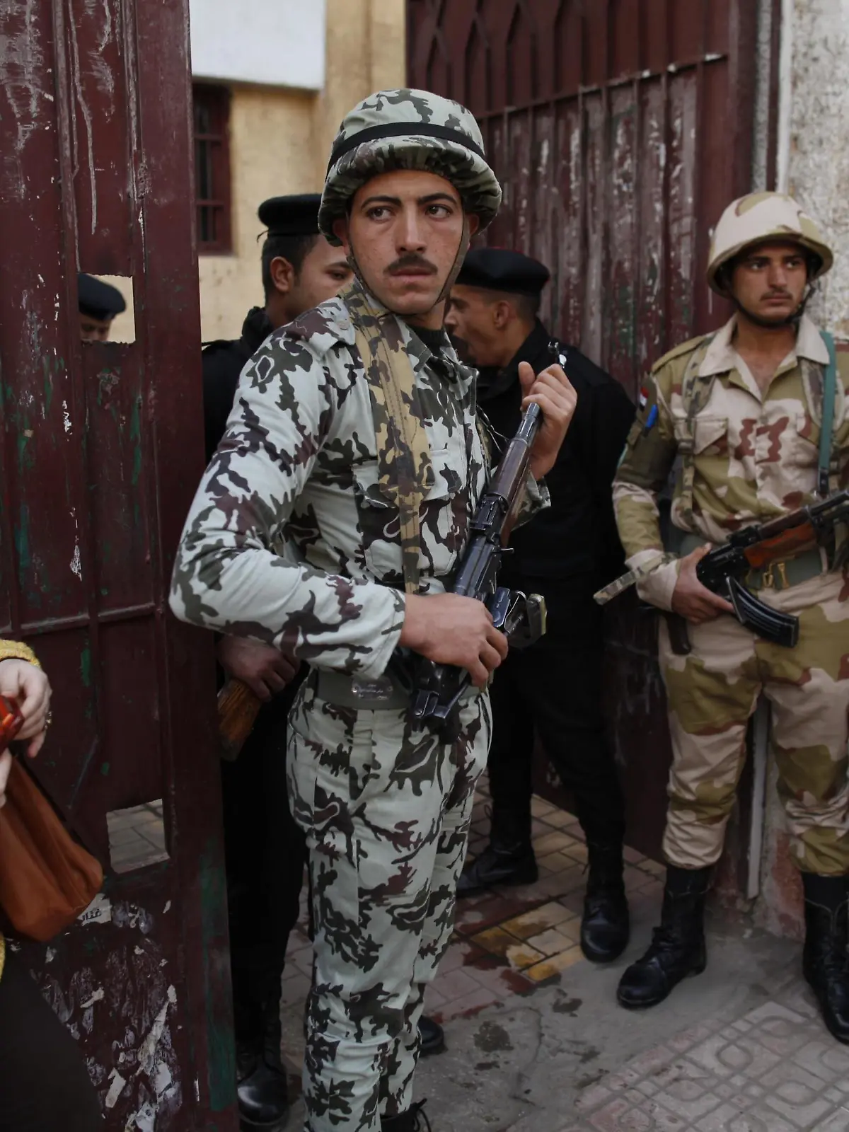 Soldiers stand guard as people wait outside a polling center to vote in referendum on Egypt's new constitution in Cairo December 15, 2012. Polling stations opened on Saturday in a referendum on a new constitution shaped by Islamist allies of Egypt's President Mohamed Mursi and which his liberal rivals say deepens divisions in the nation. REUTERS/Khaled Abdullah (EGYPT - Tags: POLITICS MILITARY)
