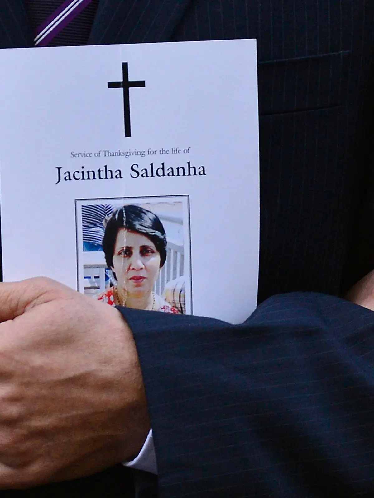 Jacintha Saldanha's widower Ben Barboza holds an order of service and the hand of his daughter Lisha (R) outside of Westminster Cathedral before a memorial service in London December 15, 2012. The family of a nurse who apparently committed suicide after taking a prank call at the hospital treating Prince William's pregnant wife Kate delivered a tearful tribute to her on Saturday, saying her death had left "an unfillable void". REUTERS/Toby Melville (BRITAIN - Tags: RELIGION CRIME LAW POLITICS)