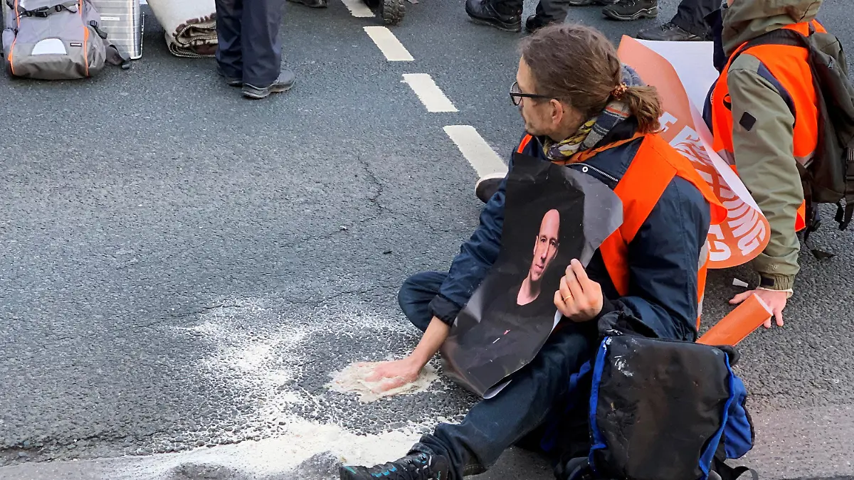 09.12.2022, Rheinland-Pfalz, Mainz: Ein Aktivist der Gruppe "Letzte Generation" sitzt mit einer auf dem Asphalt festgeklebten Hand auf einer mehrspurigen Straße am Hauptbahnhof in Mainz. «Wir sind in einem Klimanotstand und nichts wird gemacht», sagte eine Aktivistin zur Begründung der Aktion. Foto: Peter Zschunke/dpa-Zentralbild/dpa +++ dpa-Bildfunk +++