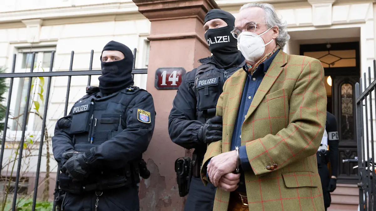 07.12.2022, Hessen, Frankfurt/Main: Bei einer Razzia gegen sogenannte «Reichsbürger» führen vermummte Polizisten, nach der Durchsuchung eines Hauses Heinrich XIII Prinz Reuß (r) zu einem Polizeifahrzeug. Die Bundesanwaltschaft hat am Mittwochmorgen mehrere Menschen aus der sogenannten Reichsbürgerszene im Zuge einer Razzia festnehmen lassen. Zahlreiche Beamte seien in mehreren Bundesländern im Einsatz, sagte eine Sprecherin der Karlsruher Behörde . Foto: Boris Roessler/dpa +++ dpa-Bildfunk +++
