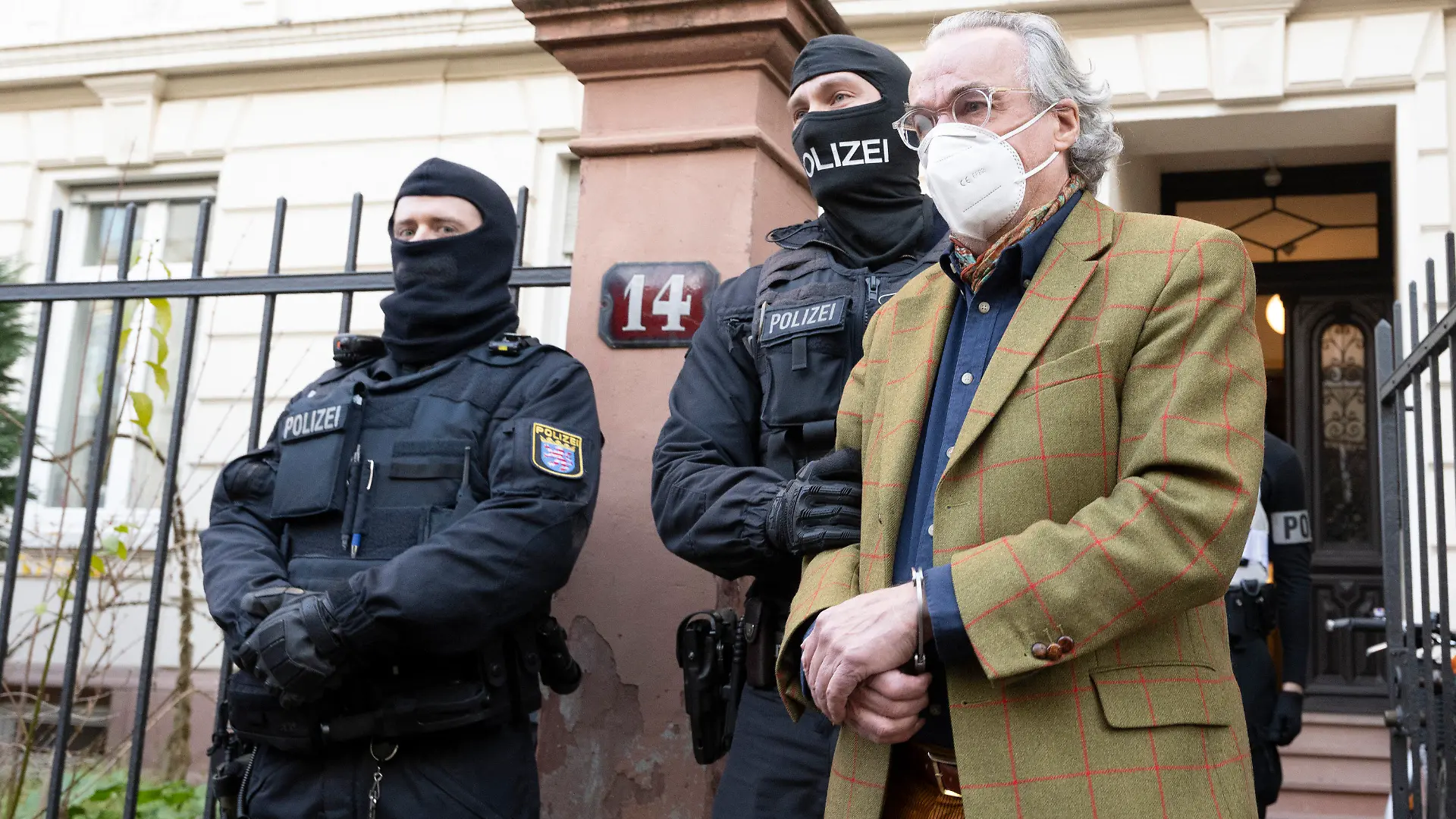 07.12.2022, Hessen, Frankfurt/Main: Bei einer Razzia gegen sogenannte «Reichsbürger» führen vermummte Polizisten, nach der Durchsuchung eines Hauses Heinrich XIII Prinz Reuß (r) zu einem Polizeifahrzeug. Die Bundesanwaltschaft hat am Mittwochmorgen mehrere Menschen aus der sogenannten Reichsbürgerszene im Zuge einer Razzia festnehmen lassen. Zahlreiche Beamte seien in mehreren Bundesländern im Einsatz, sagte eine Sprecherin der Karlsruher Behörde . Foto: Boris Roessler/dpa +++ dpa-Bildfunk +++