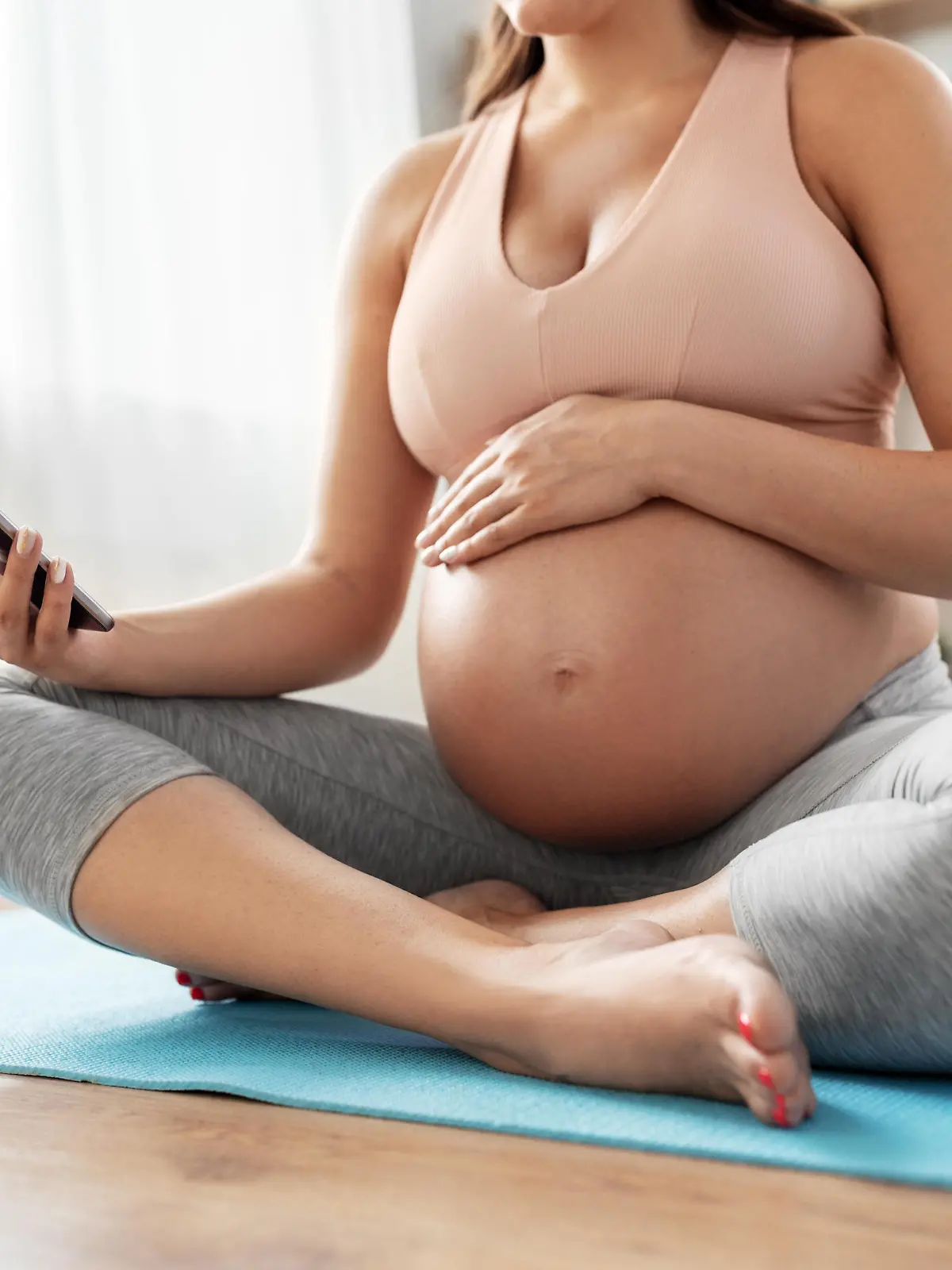 sport and people concept - happy pregnant woman with smartphone doing yoga at home