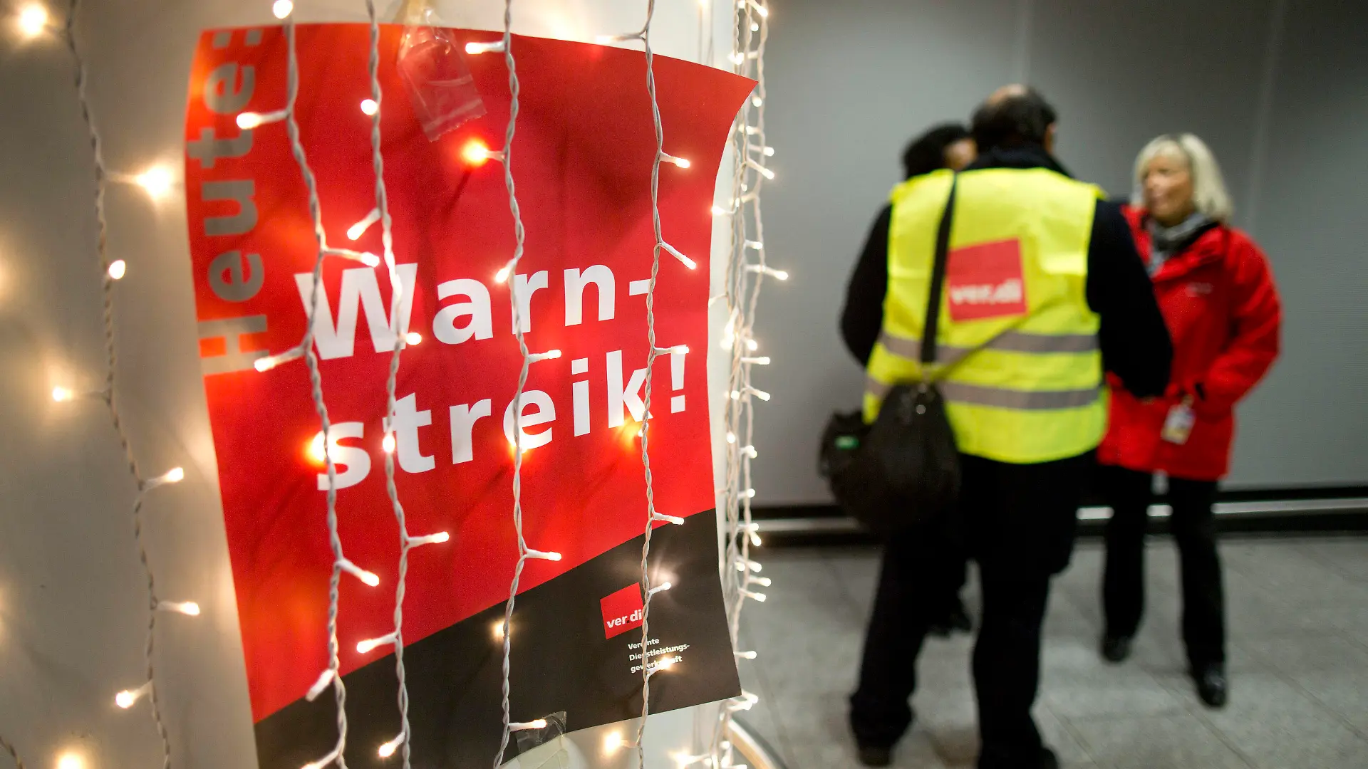 Ein Aufruf zum Warnstreik der Gewerkschaft Verdi hängt am 10.12.2012 am Flughafen von Frankfurt am Main (Hessen) hinter einer Weihnachtsbeleuchtung. Mehrere hundert Mitarbeiter des Sicherheitspersonals haben am frühen Montagmorgen an deutschen Flughäfen vorübergehend ihre Arbeit niedergelegt. In Verhandlungen macht sich die Gewerkschaft derzeit für geregelte Dienstpläne, unbefristete Arbeitsplätze und gerechte Löhne stark. Foto: Frank Rumpenhorst/dpa  +++(c) dpa - Bildfunk+++