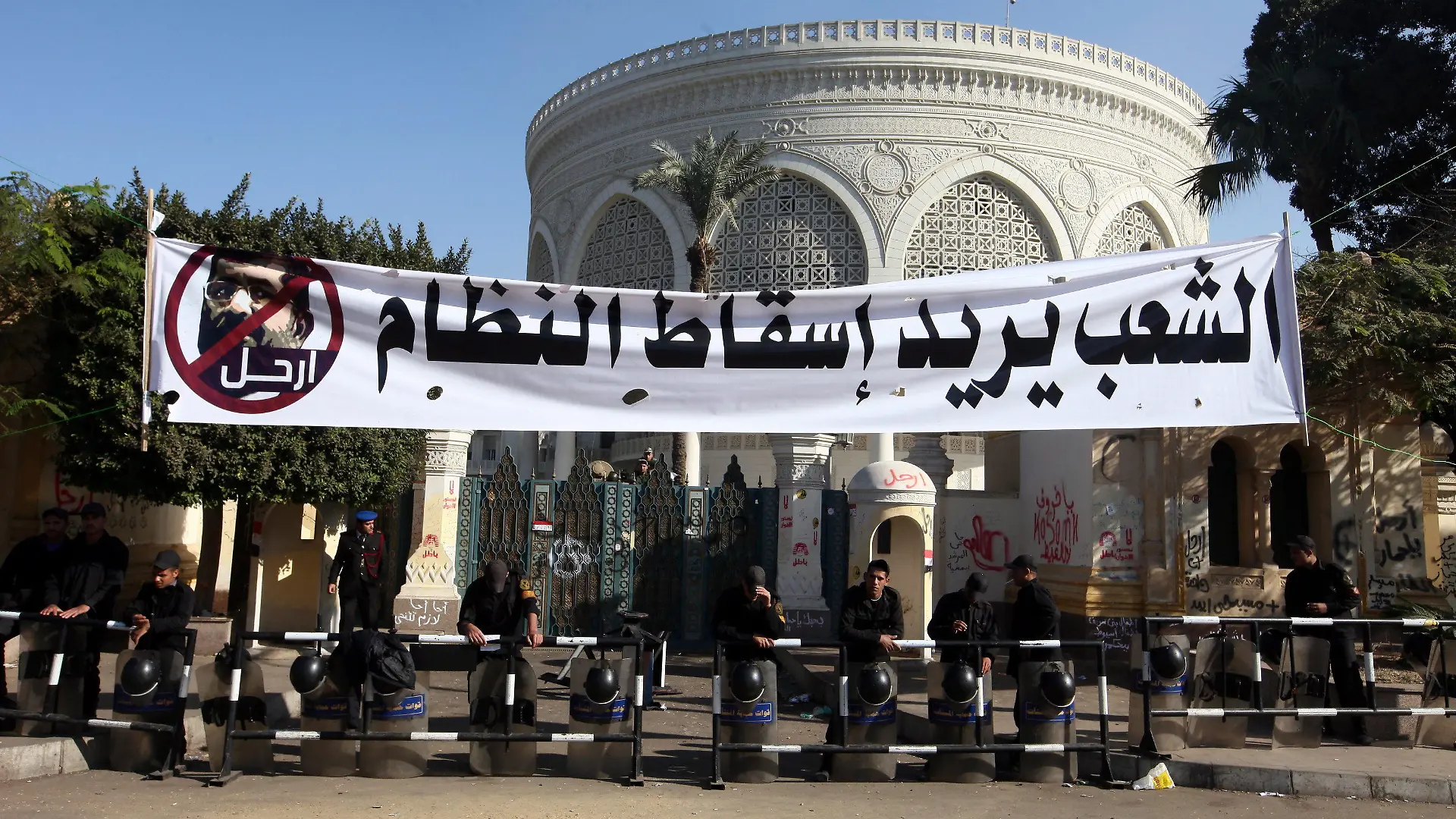 epa03503533 Egyptian security forces stand guard under a banner reading in Arabic 'The people want to bring down the regime', in front of the Presidential Palace in Cairo, Egypt, 10 December 2012. Egyptian President Mohammed Morsi has ordered the army to maintain public order and secure government institutions for a referendum later this month on a disputed draft constitution, local media reported on 10 December. he decree issued on Sunday granted army officers the authority to arrest civilians to 'maintaining public order' in the lead up to the December 15 referendum on the constitution, which was drafted by an Islamist-led constitutent assembly. EPA/KHALED ELFIQI  +++(c) dpa - Bildfunk+++
