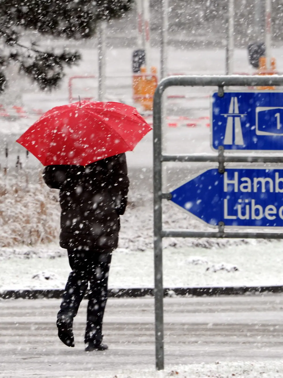 Ein Mann mit Regenschirm geht am 04.12.2012 bei Neustadt in Holstein (Schleswig-Holstein) durch den Schnee. Foto: Carsten Rehder/dpa  +++(c) dpa - Bildfunk+++