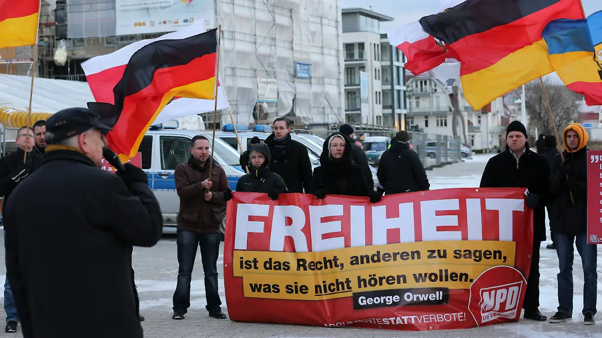 Vor dem Tagungshotel der Innenministerkonferenz (IMK) in Rostock-Warnemünde (Mecklenburg-Vorpommern) protestieren am 05.12.2012 NPD-Mitglieder gegen ein mögliches Verbot ihrer Partei. Auf ihrem Transparent heißt es: "Freiheit ist das Recht, anderen zu sagen was sie nicht hören wollen". Zum Auftakt der dreitägigen Konferenz vom 05.-07.12.2012 beraten die Innenminister von Bund und Ländern über ein neues Verbotsverfahren gegen die rechtsextreme Partei. Foto: Bernd Wüstneck/dpa +++(c) dpa - Bildfunk+++