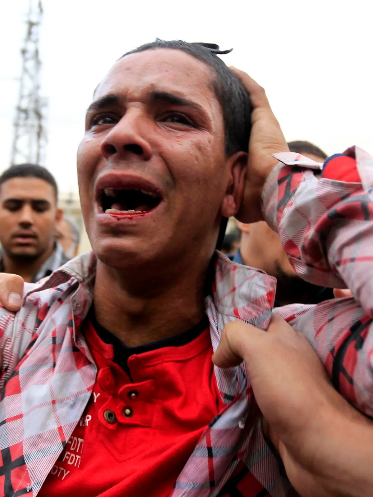 An anti-Mursi protester reacts after being hit by supporters of Egypt's President Mohammed Mursi and members of the Muslim Brotherhood during clashes outside the presidential palace in Cairo December 5, 2012. Islamists fought protesters outside the Egyptian president's palace on Wednesday, while inside the building his deputy proposed a way to end a crisis over a draft constitution that has split the most populous Arab nation. REUTERS/Mohamed Abd El Ghany (EGYPT - Tags: POLITICS CIVIL UNREST)
