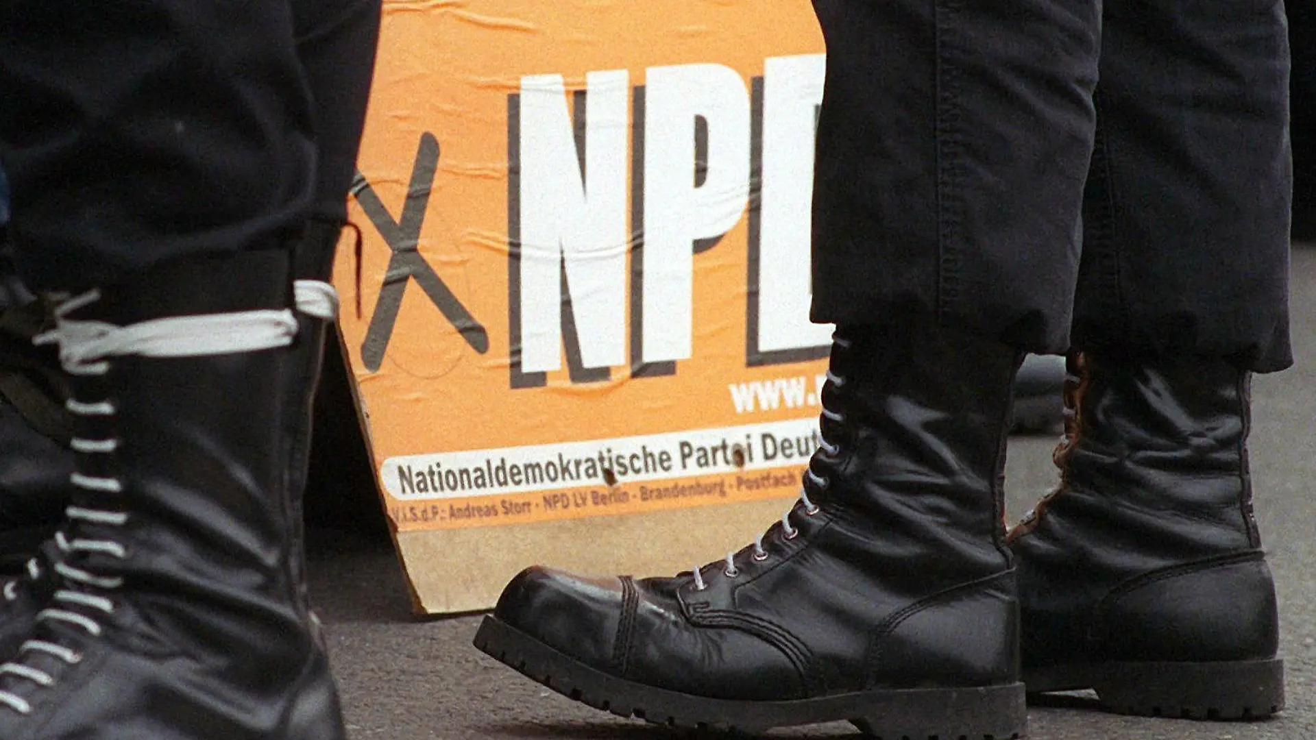 ARCHIV - NPD-Anhänger in Springerstiefeln stehen vor einem Wahlplakat der NPD (Archivfoto vom 12.3.2000). Die Innenminister des Länder und des Bundes beraten auf ihrer Herbstkonferenz in Wiesbaden ab Donnerstag (08.12.2011)) über den Kampf gegen den rechten Terror. Nach Aufdeckung der Neonazi-Mordserie wird es auch darum gehen, ob die Politik erneut ein Verbot der rechtsextremistischen NPD beantragt. Foto: Kalaene Jens dpa +++(c) dpa - Bildfunk+++