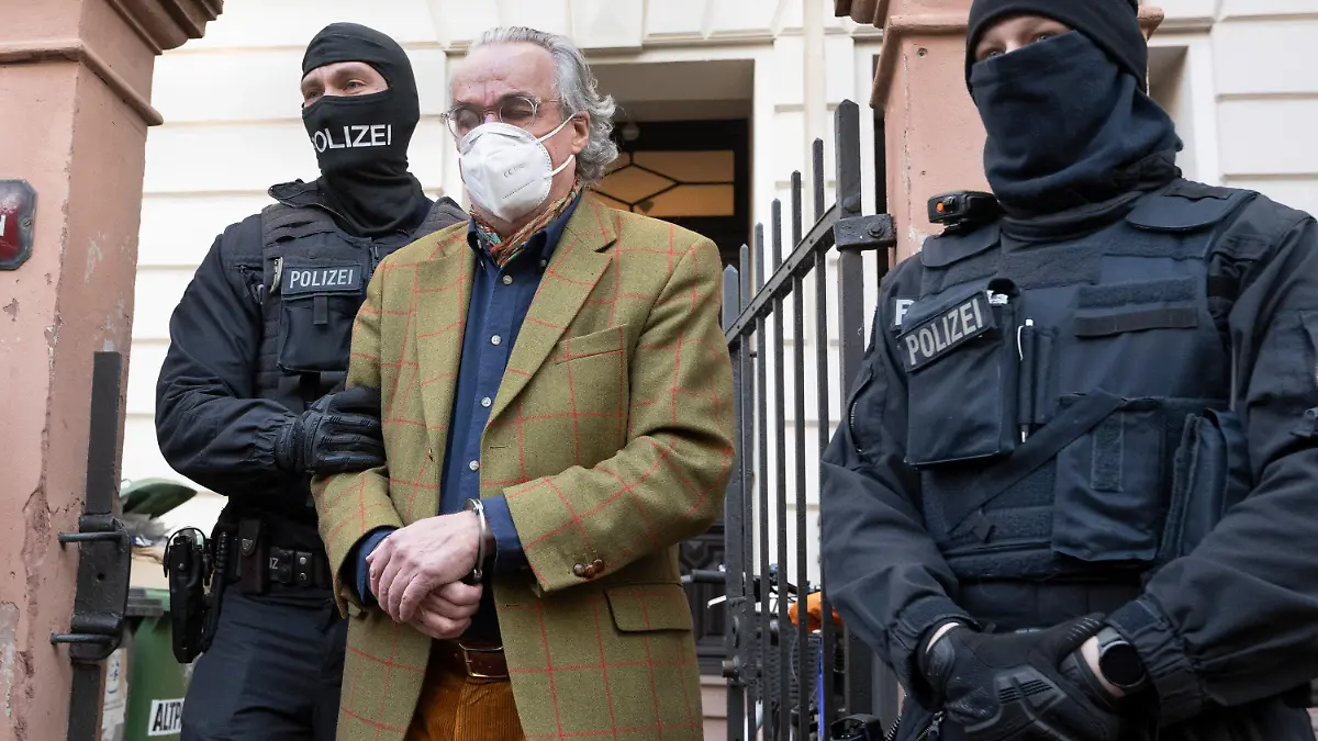 07.12.2022, Hessen, Frankfurt/Main: Bei einer Razzia gegen sogenannte «Reichsbürger» führen vermummte Polizisten, nach der Durchsuchung eines Hauses Heinrich XIII Prinz Reuß (M) zu einem Polizeifahrzeug. Er trägt dabei Handschellen. Die Bundesanwaltschaft hat am Mittwochmorgen mehrere Menschen aus der sogenannten Reichsbürgerszene im Zuge einer Razzia festnehmen lassen. Zahlreiche Beamte seien in mehreren Bundesländern im Einsatz, sagte eine Sprecherin der Karlsruher Behörde . Foto: Boris Roessler/dpa +++ dpa-Bildfunk +++