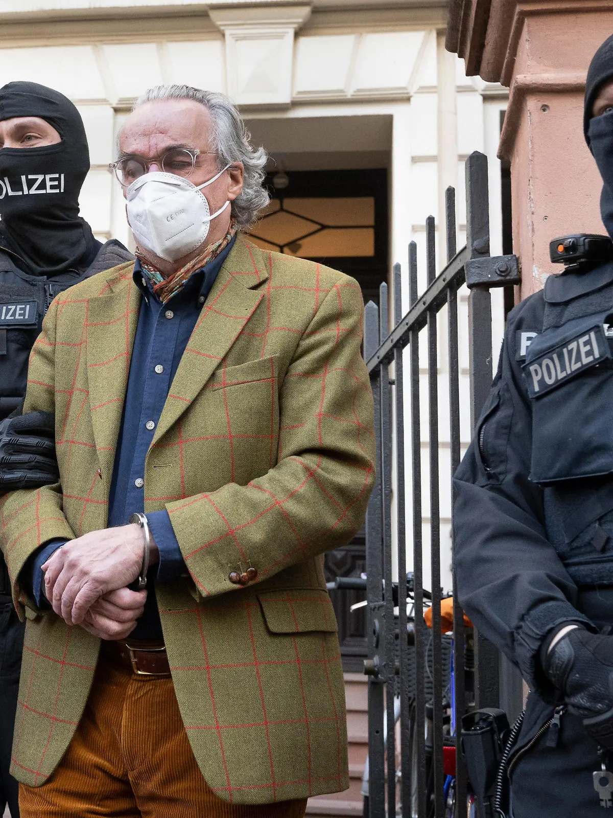 07.12.2022, Hessen, Frankfurt/Main: Bei einer Razzia gegen sogenannte «Reichsbürger» führen vermummte Polizisten, nach der Durchsuchung eines Hauses Heinrich XIII Prinz Reuß (M) zu einem Polizeifahrzeug. Er trägt dabei Handschellen. Die Bundesanwaltschaft hat am Mittwochmorgen mehrere Menschen aus der sogenannten Reichsbürgerszene im Zuge einer Razzia festnehmen lassen. Zahlreiche Beamte seien in mehreren Bundesländern im Einsatz, sagte eine Sprecherin der Karlsruher Behörde . Foto: Boris Roessler/dpa +++ dpa-Bildfunk +++