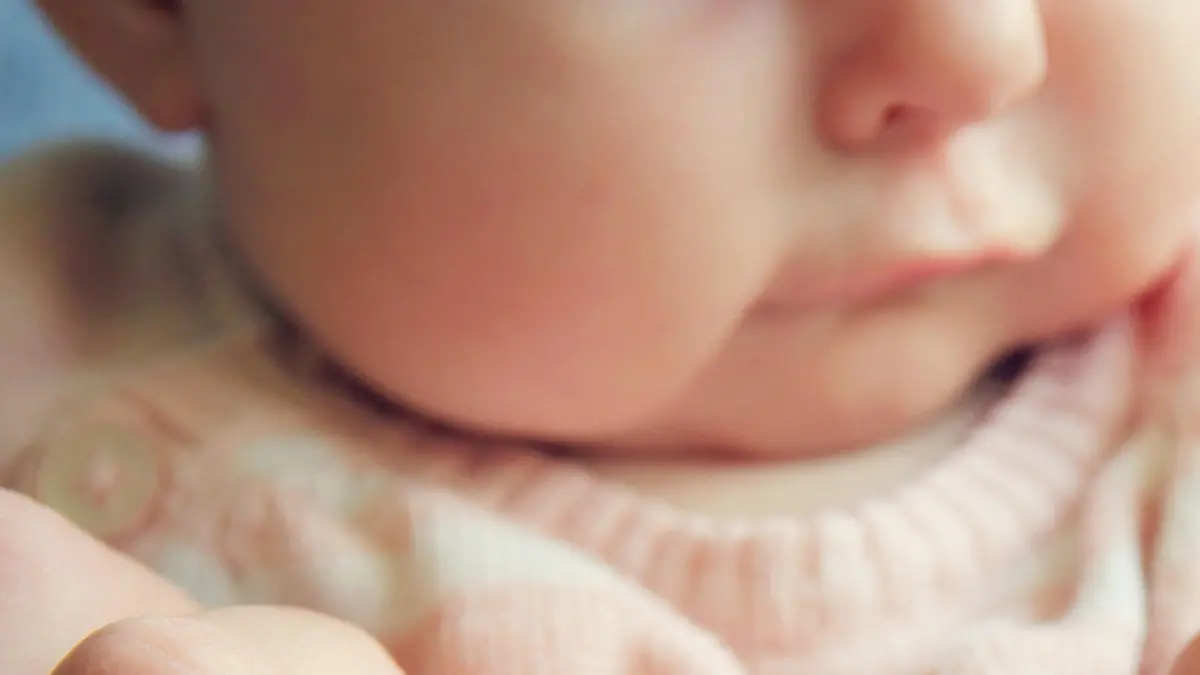 Focus on the hands of a 3 month old baby girl holding the fingers of her father. Vintage style color filter.