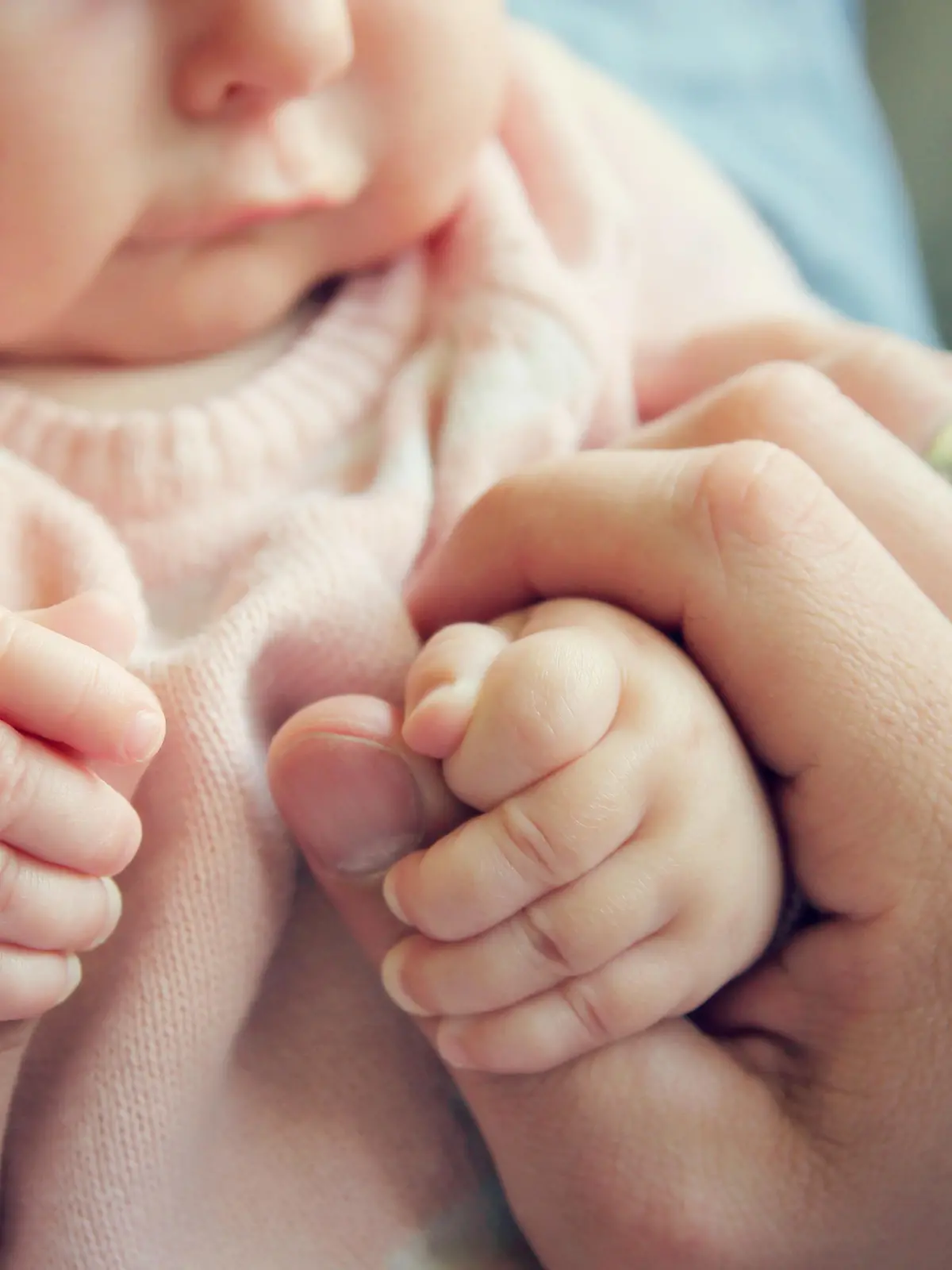 Focus on the hands of a 3 month old baby girl holding the fingers of her father.  Vintage style color filter.