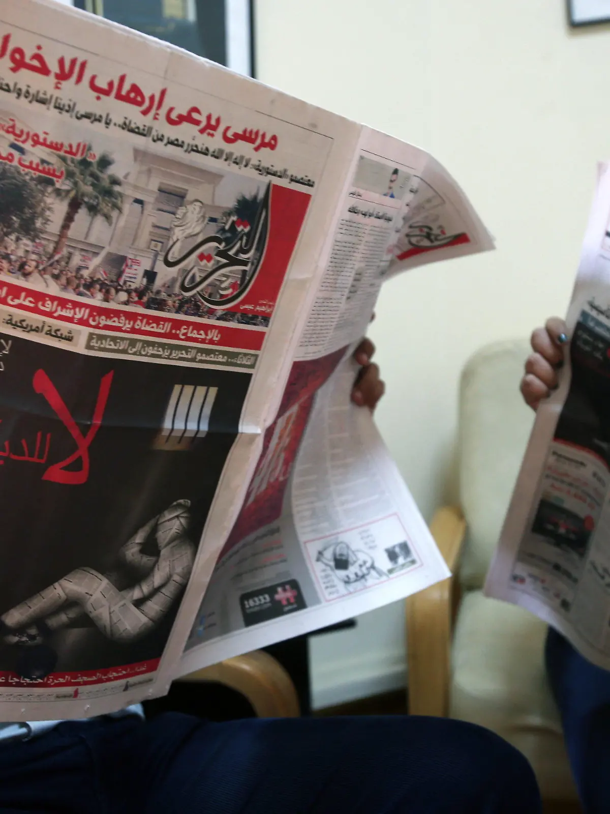 epa03495004 Unidentified Egyptian people read Al-Tahrir (L) and Masr el Youm independent newspapers, a front page (L) shows a black poster of a human covered in newspaper pages, chained in a celll, an inscription reading in Arabic 'a constitution that cancels rights and chains freedoms. No to dictatorship', in Cairo Egypt, 03 December 2012. Several independent and opposition Egyptian newspapers will suspend publication on 04 December to protest what they described as President Mohammed Morsi's 'dictatorship', as demonstrations against Morsi's rule continue to spread on 03 December. EPA/ANDRE PAIN  +++(c) dpa - Bildfunk+++