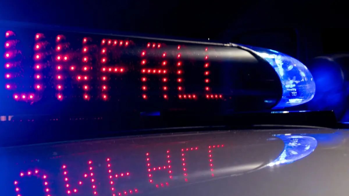 ARCHIV - 30.06.2018, Sachsen, Dresden: Das Blaulicht auf einem Polizeiauto leuchtet in der Dunkelheit, während auf dem Display der Hinweis «Unfall» zu lesen ist. Das Oberlandesgericht München verhandelt am 24.05.2019 in dem Rechtsstreit zwischen der Versicherung und einem Autofahrer, der seinen Sportwagen bei einem Unfall geschrottet hat. Er soll - mutmaßlich im Rahmen eines Autorennens - viel zu schnell gefahren sein. An seinem Wagen entstand Totalschaden; es geht um mehr als 80 000 Euro. Das Strafverfahren zu dem Unfall lief am Gericht in Siegburg. Foto: Monika Skolimowska/ZB/dpa +++ dpa-Bildfunk +++