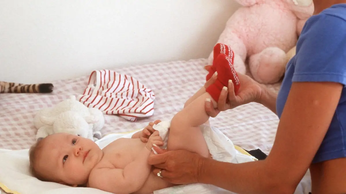 Eine junge Mutter wechselt ihrem Baby die Windeln. (Aufnahme von 1999).