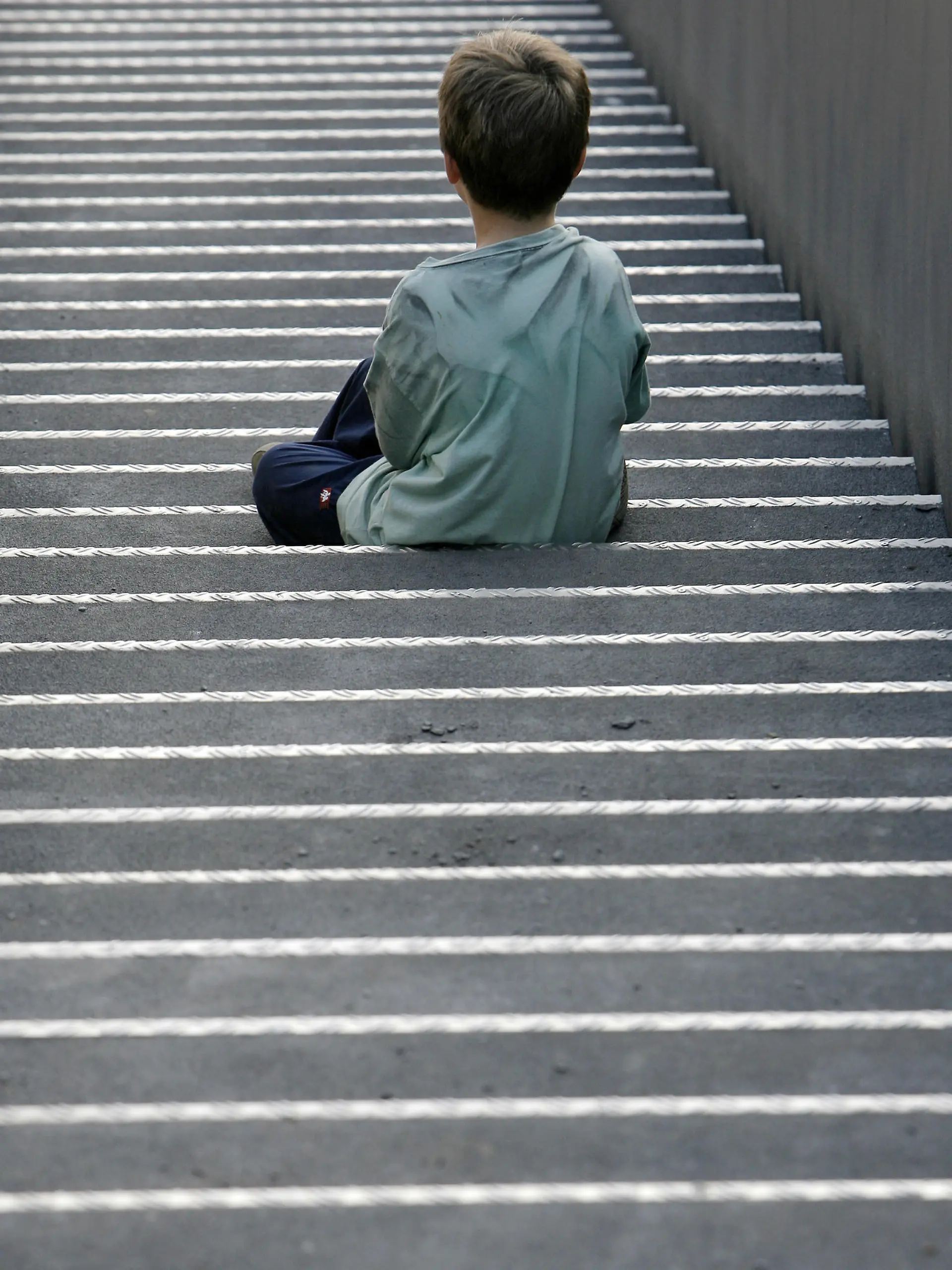 Ein kleiner Junge sitzt allein auf einer langen Treppe, aufgenommen am 23.09.2007 in Neukirchen-Vluyn. Foto: Arno Burgi  +++(c) dpa - Report+++