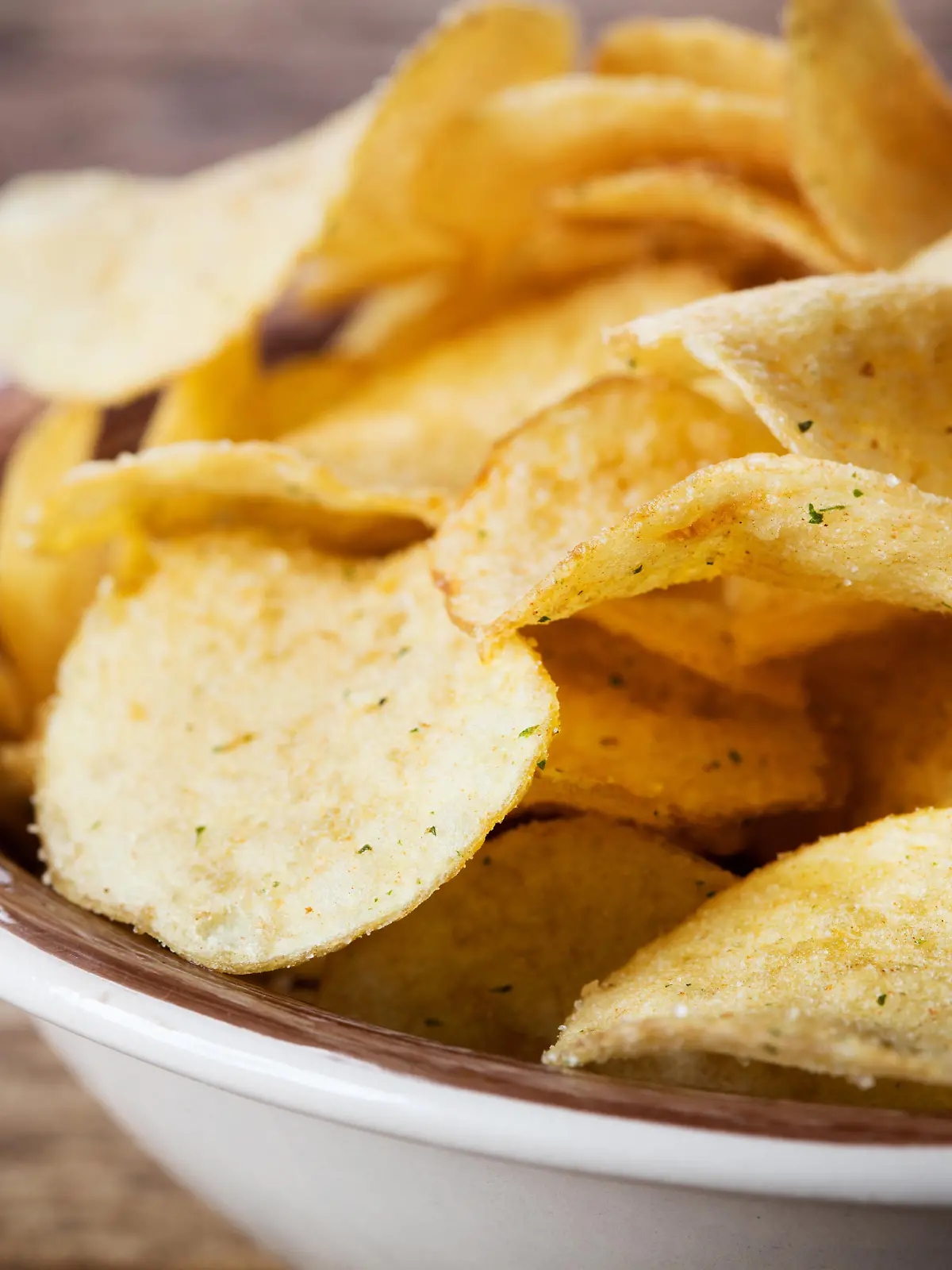 heap of potato chips in bowl on wooden background