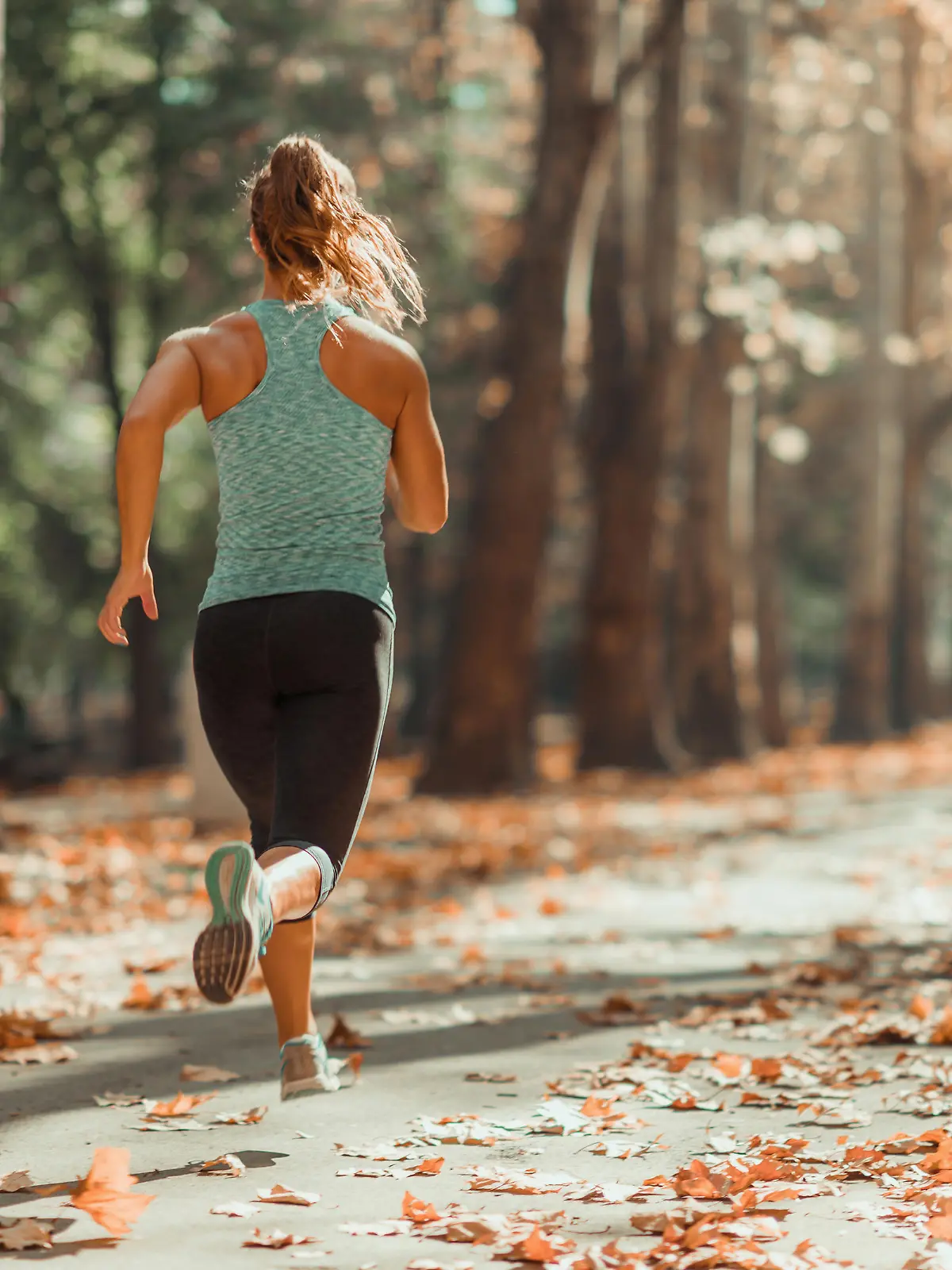 Woman Jogging Outdoors In Autumn in Public Park