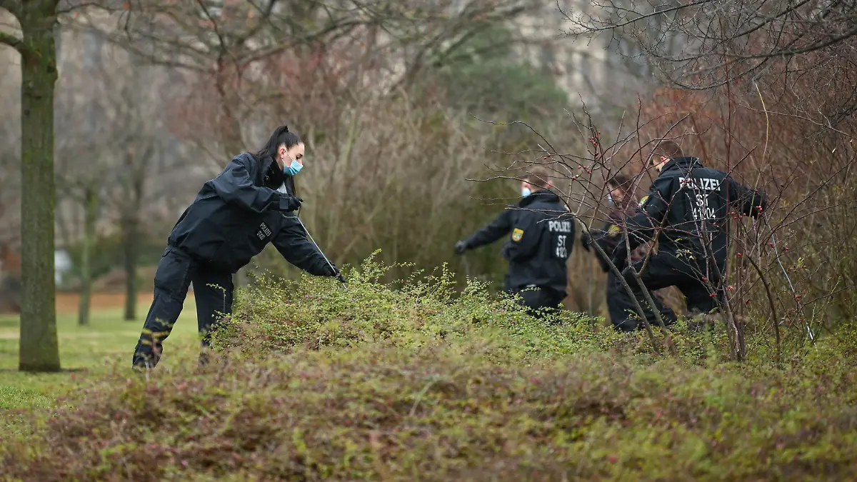 ARCHIV - 28.12.2021, Sachsen-Anhalt, Halle (Saale): Eine Polizistin durchsucht zusammen mit Kollegen ein Gebüsch. Am Zaun der Halleschen Stadtwirtschaft wurde am Abend zuvor eine Babyleiche gefunden. Die Kriminalpolizei sicherte vor Ort umfangreiche Spuren. (Zu dpa: «Ein Jahr nach Fund einer Babyleiche - 38-Jährige festgenommen«) Foto: Heiko Rebsch/dpa-Zentralbild/dpa +++ dpa-Bildfunk +++