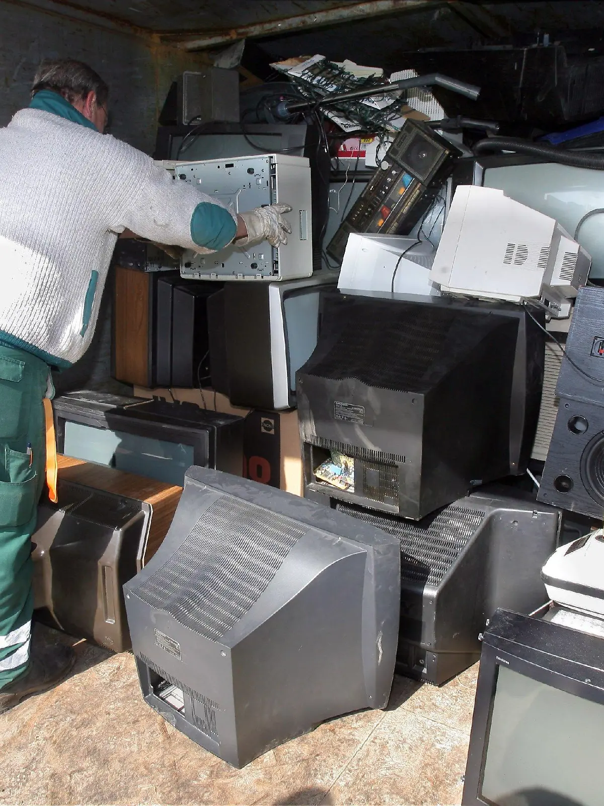 Ein Mitarbeiter der Berliner Stadtreinigung BSR stapelt am Mittwoch (22.03.2006) in einem Container mit Elektrogeräten auf einem Recyclinghof der BSR in Berlin Fernsehgeräte und Monitore. Von Freitag (24.03.2006) an müssen die Bürger ihre ausgedienten Elektrogeräte wie etwa Toaster, Drucker, Computer oder Rasierapparat sachgerecht entsorgen lassen. Kommunale Sammelstellen nehmen den Schrott kostenlos entgegen. Die Kosten für die Entsorgung tragen künftig die Gerätehersteller. Foto: Tim Brakemeier dpa/lbn  +++(c) dpa - Bildfunk+++