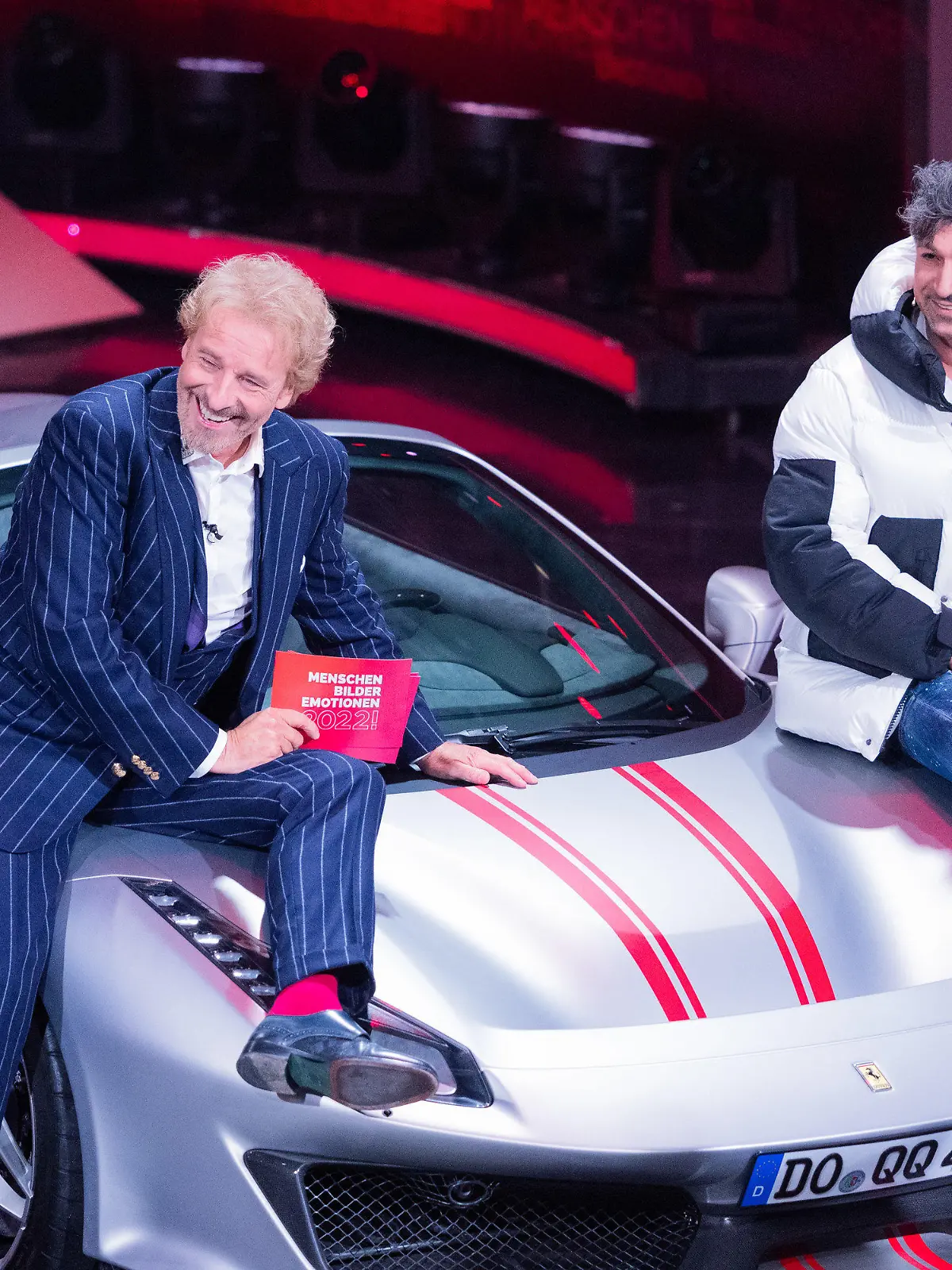 11.12.2022, Nordrhein-Westfalen, Hürth: Thomas Gottschalk (l), Moderator, und  Lotto-Millionär Kürsat Yildirim alias "Chico" sitzen auf einem Ferrari beim RTL-Jahresrückblick "Menschen, Bilder, Emotionen 2022" im Studio. Foto: Rolf Vennenbernd/dpa +++ dpa-Bildfunk +++