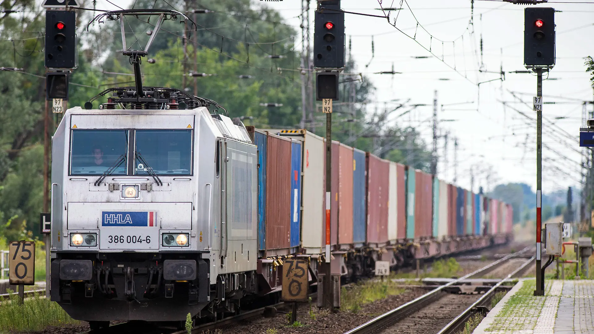 ARCHIV - 10.08.2020, Brandenburg, Wustermark: Ein von einer E-Lok der Hamburger Hafen und Logistik AG (HHLA) gezogener Güterzug passiert den Bahnhof des Dorfes Priort in der Gemeinde Wustermark. Der Interessenverband Allianz pro Schiene mahnt mehr Tempo bei der Elektrifzierung von Gleisstrecken in Deutschland an. (Zu dpa "chienenverband fordert mehr Tempo bei Elektrifizierung") Foto: Soeren Stache/dpa-Zentralbild/dpa +++ dpa-Bildfunk +++