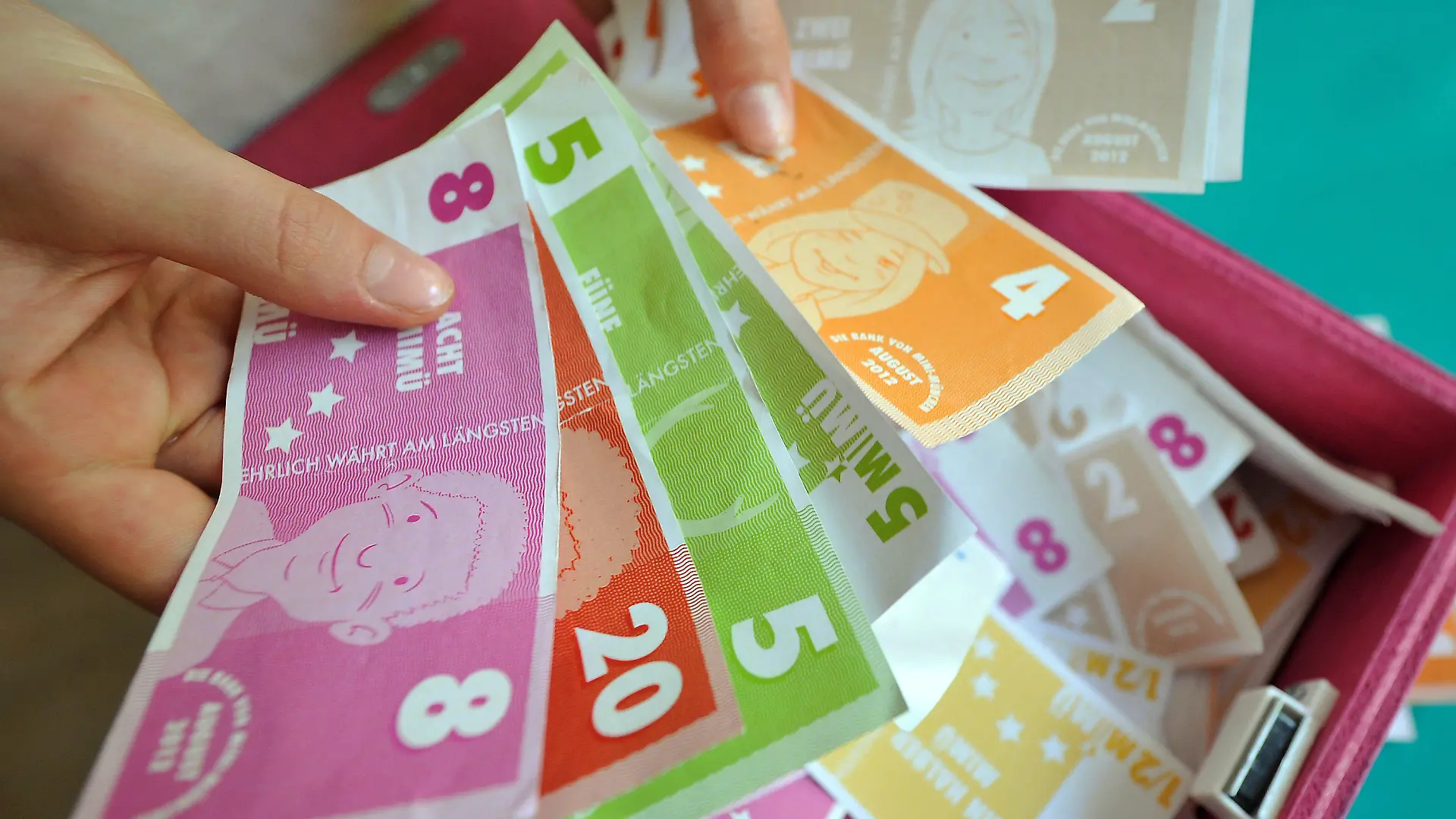 Kinderhände zählen "MiMüs", das Geld von Mini-München, am Dienstag (07.08.2012) im Olympiapark in München (Oberbayern). Im Rathaus regiert der OB, die Bäckerei verkauft frische Semmeln und im Handwerkerhof wird gesägt, geleimt, genäht und gehämmert - Mini-München bietet Kindern als das, was es im richtigen Leben auch gibt. Nur die Eltern haben hier nichts zu melden. Die Stadt im Kleinformat wird alle zwei Jahre vom Verein Kultur und Spielraum im Auftrag der Stadt München organisiert. Foto: Frank Leonhardt dpa/lby (zu KORR: "Elternfreie Zone im Mini-München: Hier haben Kinder das Sagen" am 08.08.2012)  +++(c) dpa - Bildfunk+++