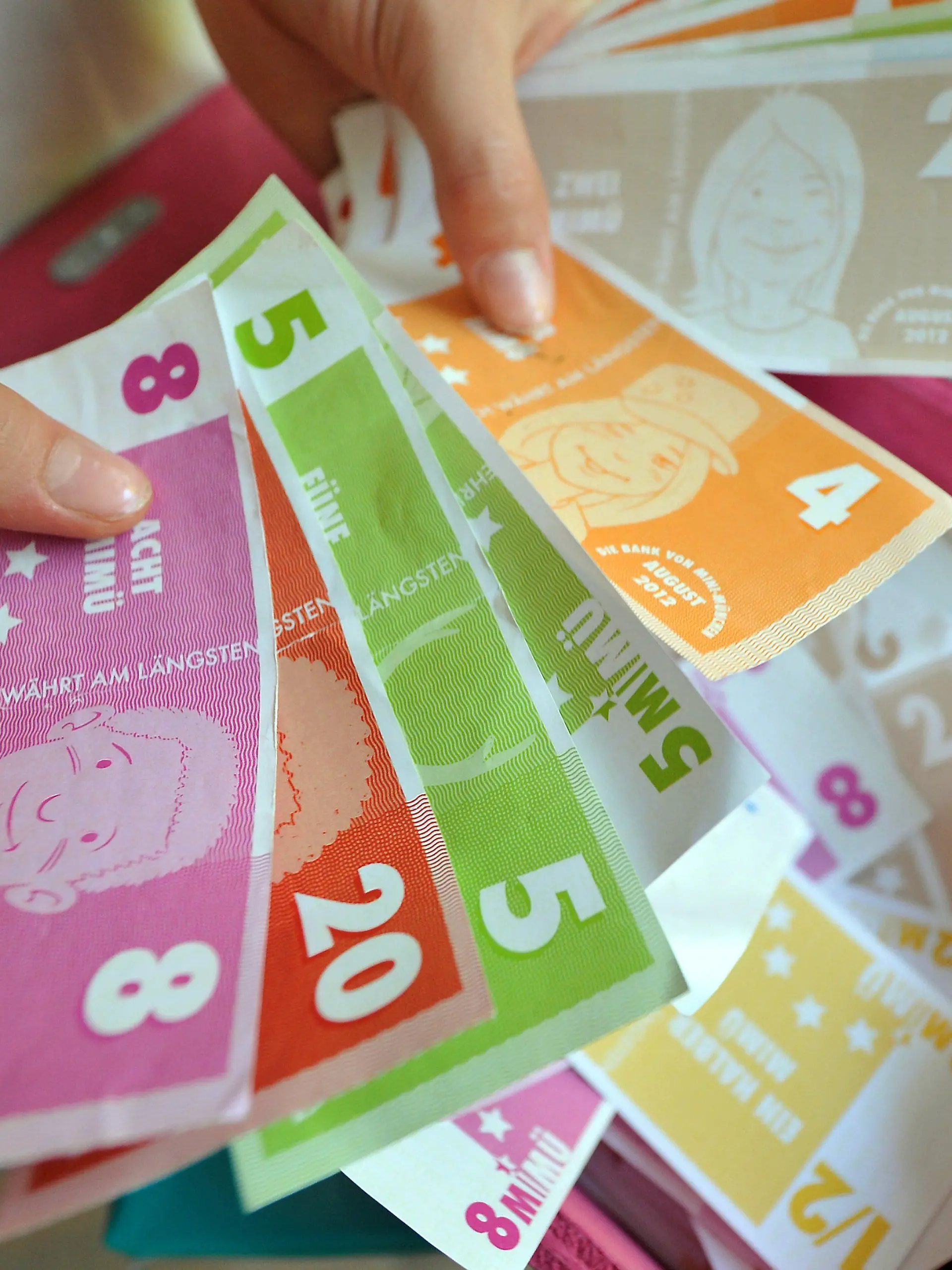 Kinderhände zählen "MiMüs", das Geld von Mini-München, am Dienstag (07.08.2012) im Olympiapark in München (Oberbayern). Im Rathaus regiert der OB, die Bäckerei verkauft frische Semmeln und im Handwerkerhof wird gesägt, geleimt, genäht und gehämmert - Mini-München bietet Kindern als das, was es im richtigen Leben auch gibt. Nur die Eltern haben hier nichts zu melden. Die Stadt im Kleinformat wird alle zwei Jahre vom Verein Kultur und Spielraum im Auftrag der Stadt München organisiert. Foto: Frank Leonhardt dpa/lby (zu KORR: "Elternfreie Zone im Mini-München: Hier haben Kinder das Sagen" am 08.08.2012)  +++(c) dpa - Bildfunk+++