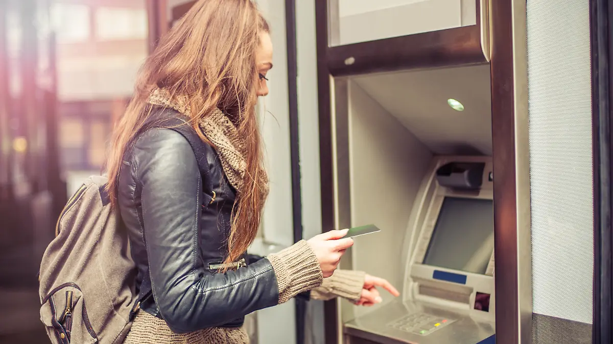 Young woman withdrawing money from credit card at ATM