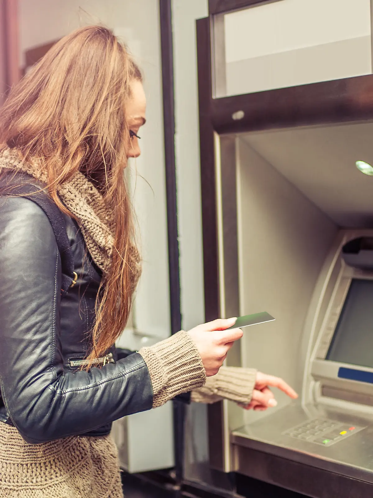 Young woman withdrawing money from credit card at ATM