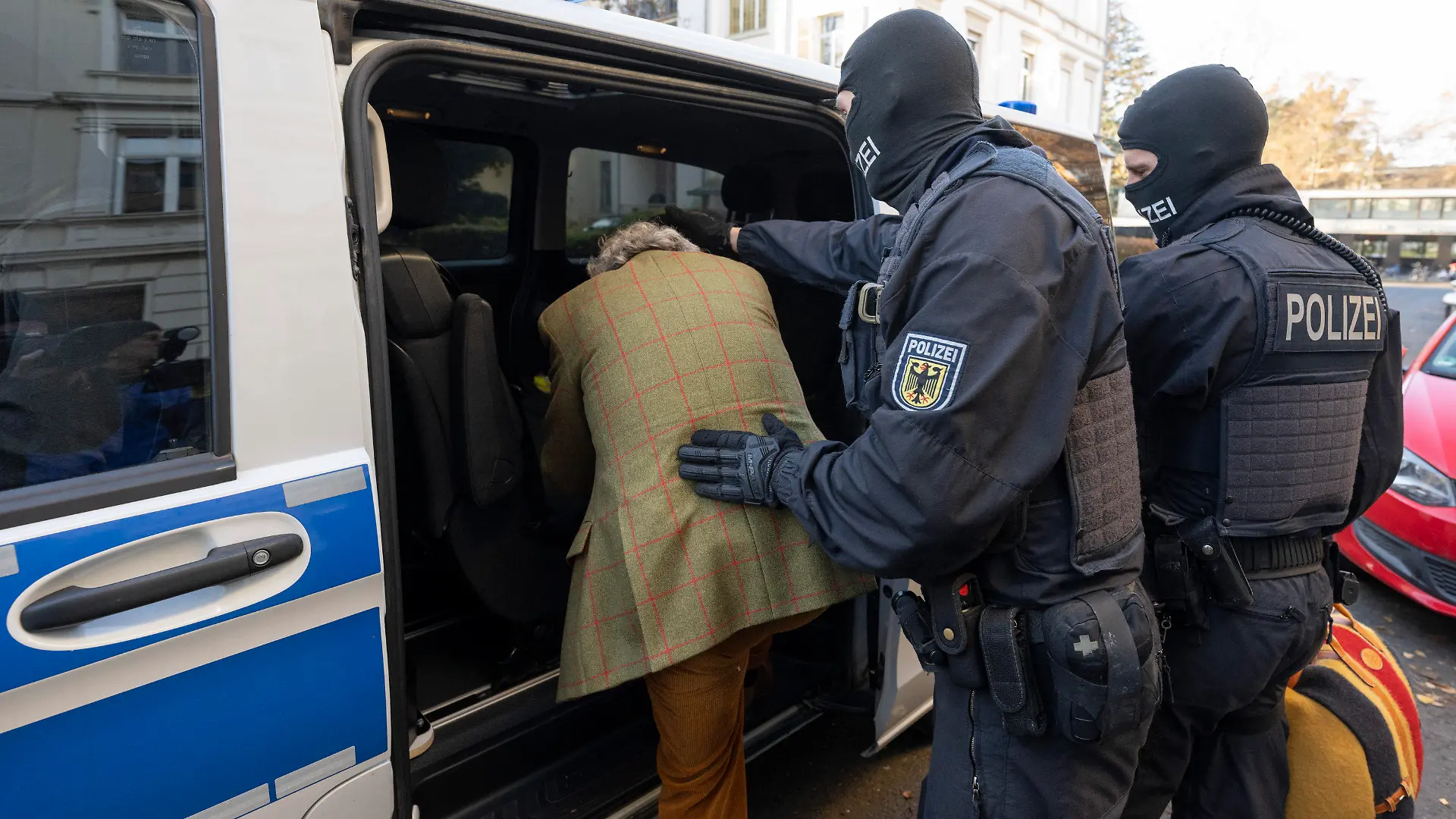 07.12.2022, Hessen, Frankfurt/Main: Bei einer Razzia gegen sogenannte «Reichsbürger» führen vermummte Polizisten, nach der Durchsuchung eines Hauses Heinrich XIII Prinz Reuß zu einem Polizeifahrzeug. Die Bundesanwaltschaft hat am Mittwochmorgen mehrere Menschen aus der sogenannten Reichsbürgerszene im Zuge einer Razzia festnehmen lassen. Zahlreiche Beamte seien in mehreren Bundesländern im Einsatz, sagte eine Sprecherin der Karlsruher Behörde . Foto: Boris Roessler/dpa +++ dpa-Bildfunk +++