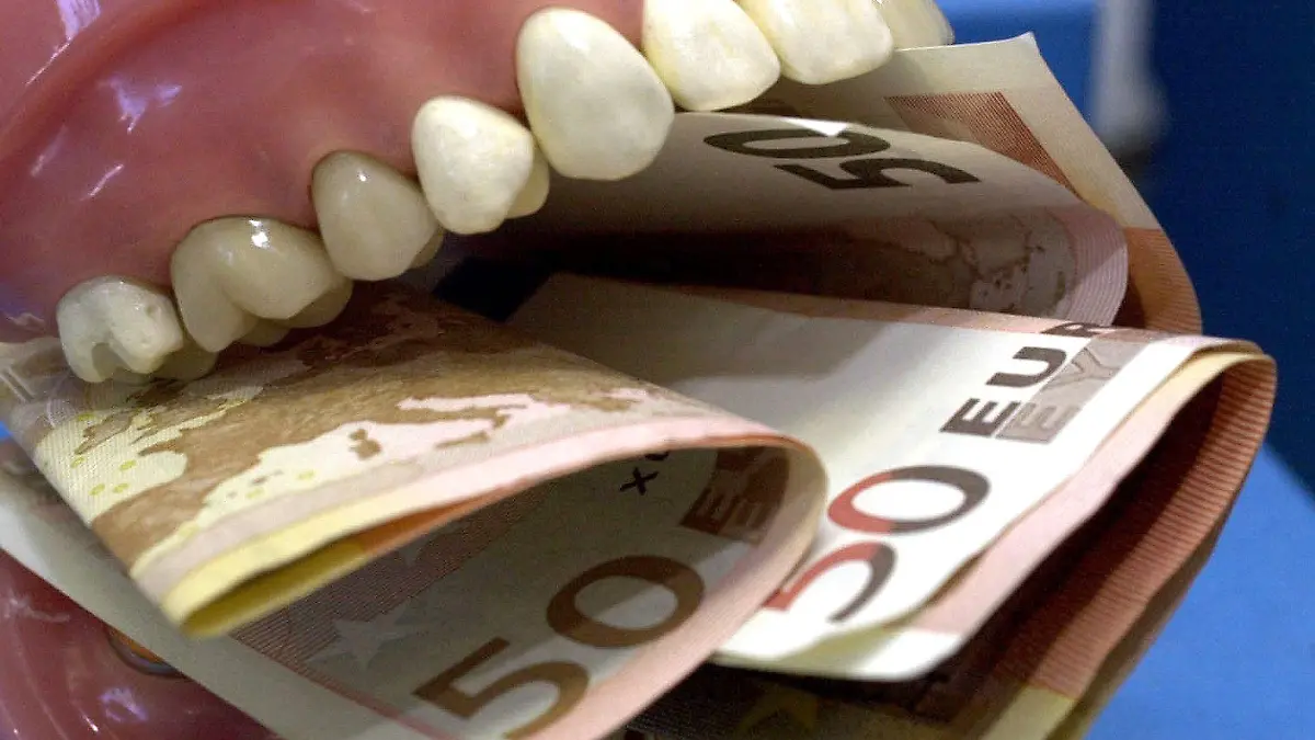 ARCHIV - ILLUSTRATION - Geldscheine stecken am 13.02.2003 in Potsdam zwischen den Zähnen einer Zahnprothese. Die gesetzlichen Krankenkassen wollen Zahnarztrechnungen künftig stärker kontrollieren. Nach Aussage eines Sprechers des Spitzenverbandes der Gesetzlichen Krankenversicherung (GKV) reagieren die Kassen damit auf Beschwerden von Versicherten über zu hohe Rechnungen. Foto: Nestor Bachmann dpa (Zu dpa «Kassen wollen Zahnarzt-Rechnungen stärker kontrollieren» vom 10.04.2012)  +++(c) dpa - Bildfunk+++
