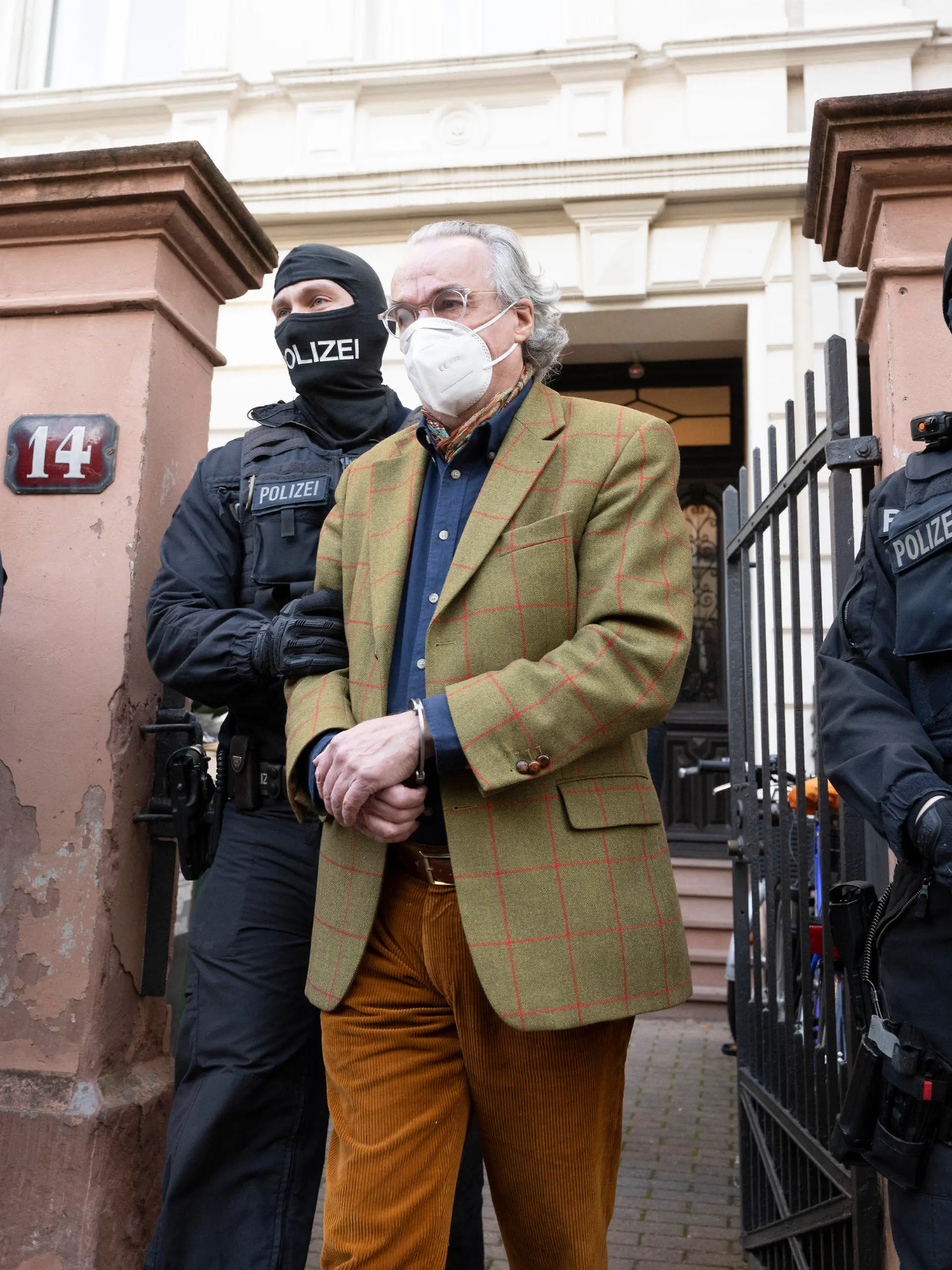dpatopbilder - 07.12.2022, Hessen, Frankfurt/Main: Bei einer Razzia gegen sogenannte «Reichsbürger» führen vermummte Polizisten, nach der Durchsuchung eines Hauses Heinrich XIII Prinz Reuß (2.v.r.) zu einem Polizeifahrzeug. Die Bundesanwaltschaft hat am Mittwochmorgen mehrere Menschen aus der sogenannten Reichsbürgerszene im Zuge einer Razzia festnehmen lassen. Zahlreiche Beamte seien in mehreren Bundesländern im Einsatz, sagte eine Sprecherin der Karlsruher Behörde . Foto: Boris Roessler/dpa +++ dpa-Bildfunk +++